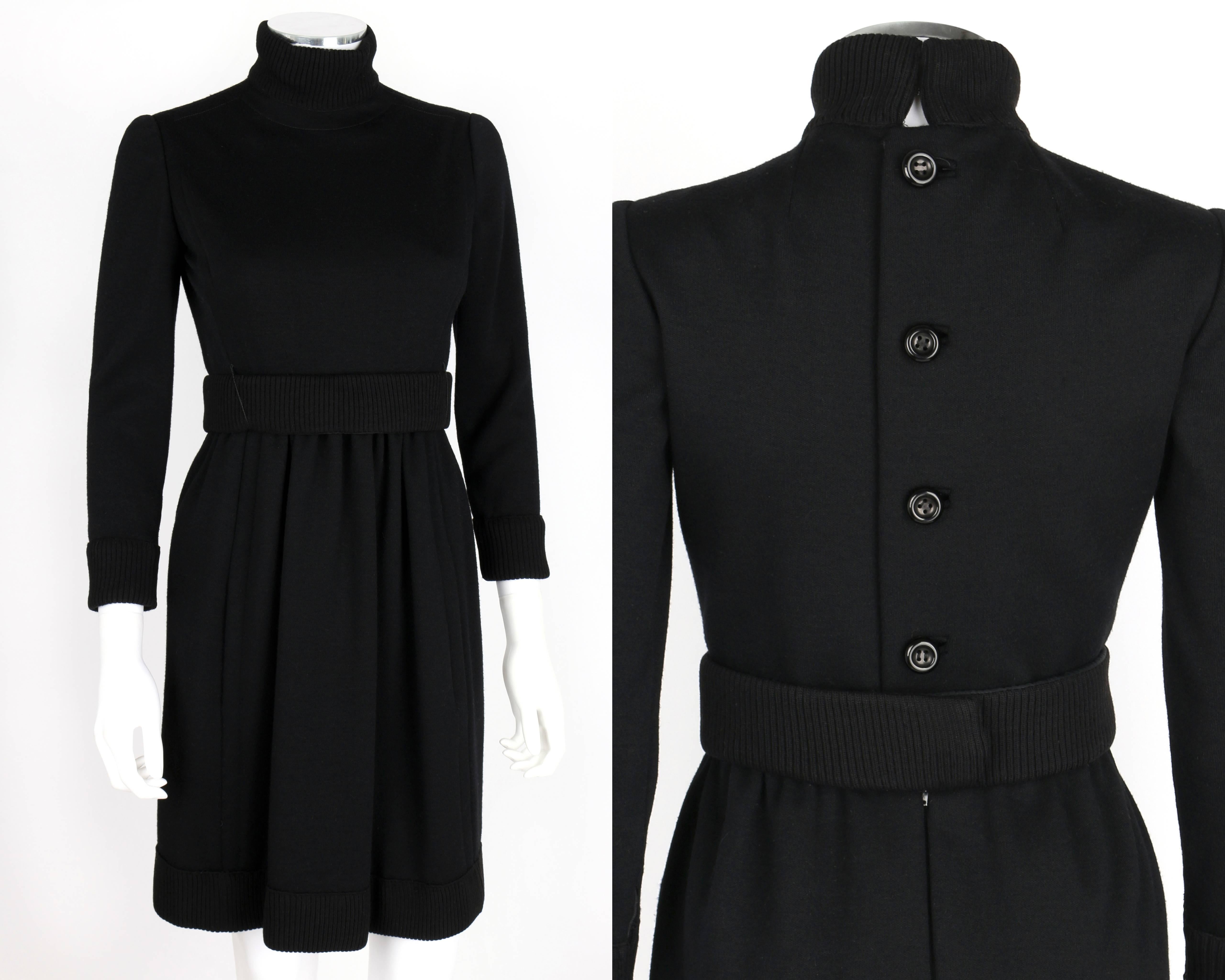 Vintage c.1960's Donald Brooks black mod coat dress. High ribbed collar closes with hooks and eyes. Dress buttons and zips at back. 3/4 sleeves zip at cuffs. Ribbed cuffs and hem. Above the knee length. Matching ribbed belt. Lined. Unmarked Fabric