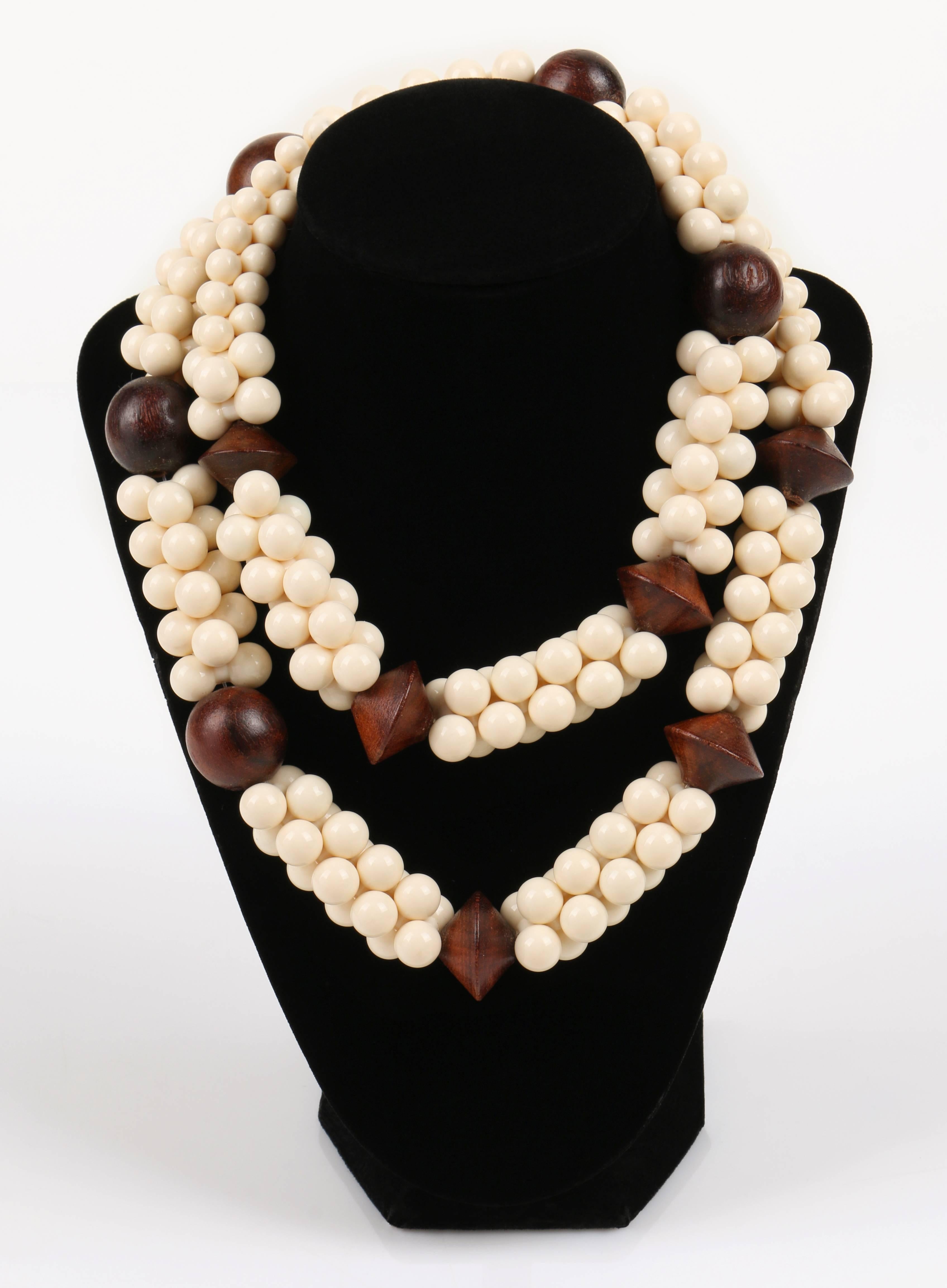 Vintage c.1967 Yves Saint Laurent African Collection chunky wood and ivory resin bead necklace. Resin interlocking beads are quar strung and divided with large wood beads. Gold tone YSL logo hook clasp. Wood beads measure approximately 1/2