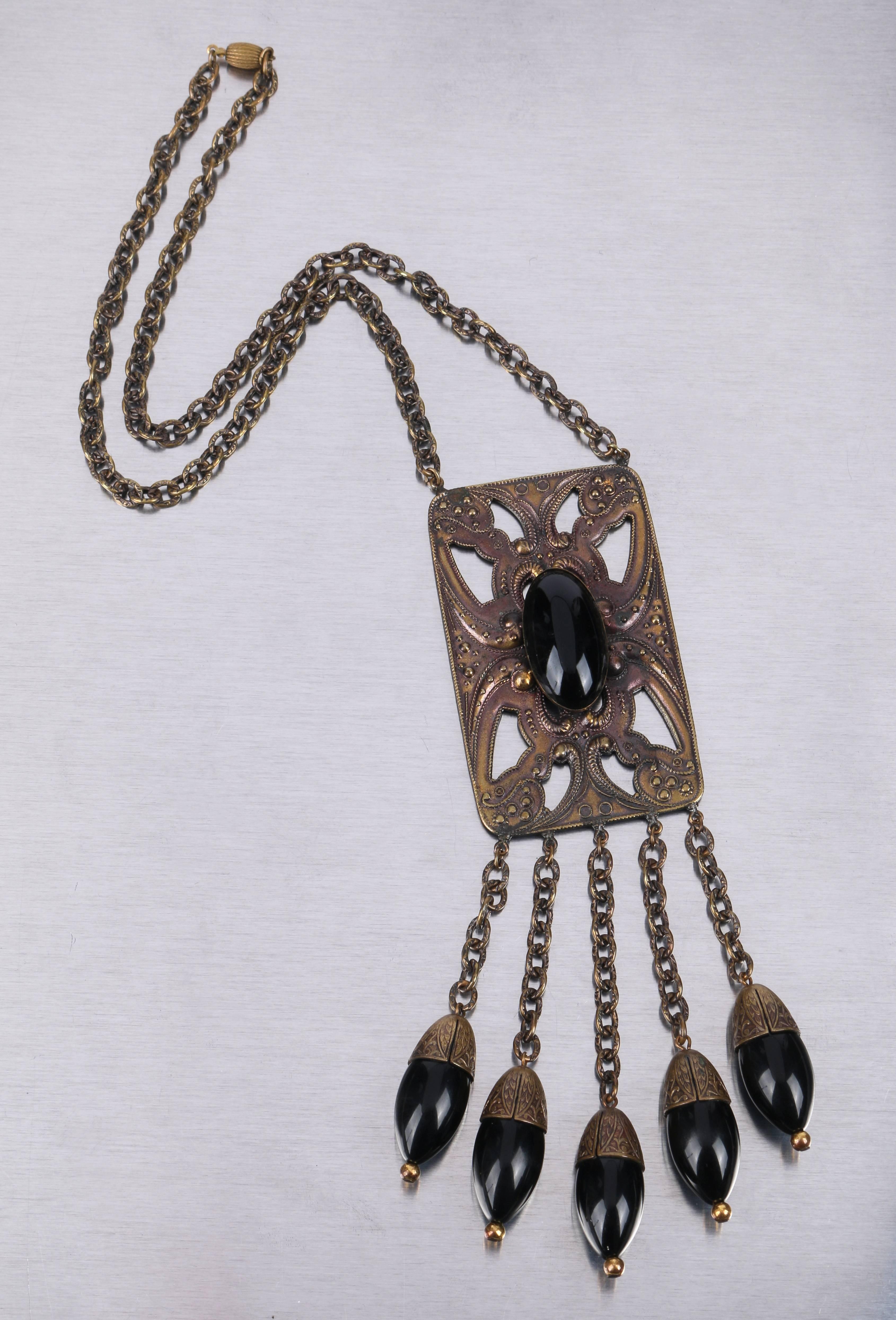 Vintage c.1920's Art Deco bronze tone large open cut pendant with black onyx glass cabochon bead dangles on open link chain necklace. Large rectangular open cut carved scroll design bronze tone pendant measures approximately 3