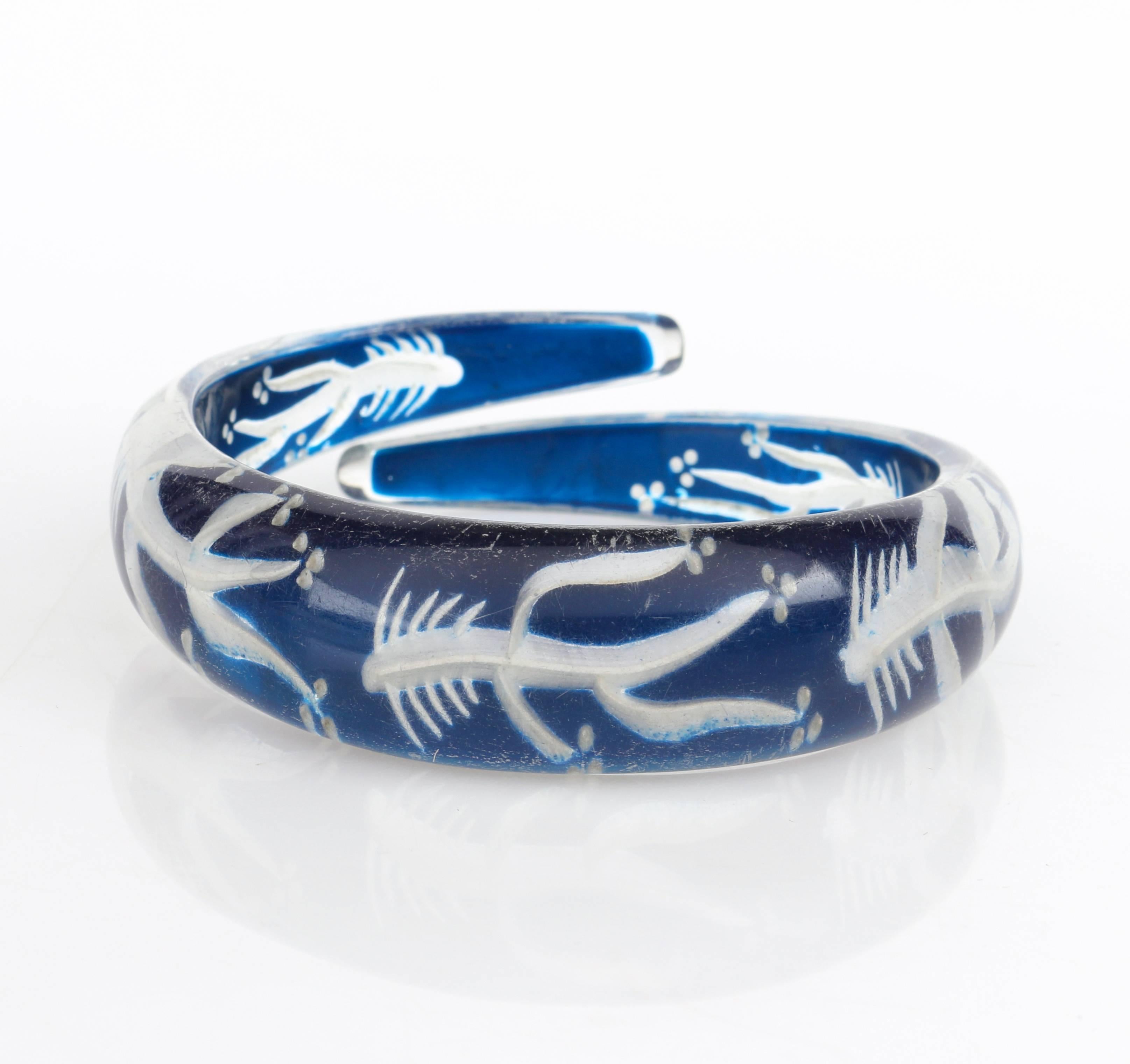 Extremely rare vintage circa late 1930's - early 1940's clear plastic with blue color back etched fish bone design bypass bangle bracelet. Reversed hand carved horizontal fish bone pattern repeated around bracelet. Back of bracelet is a deep blue