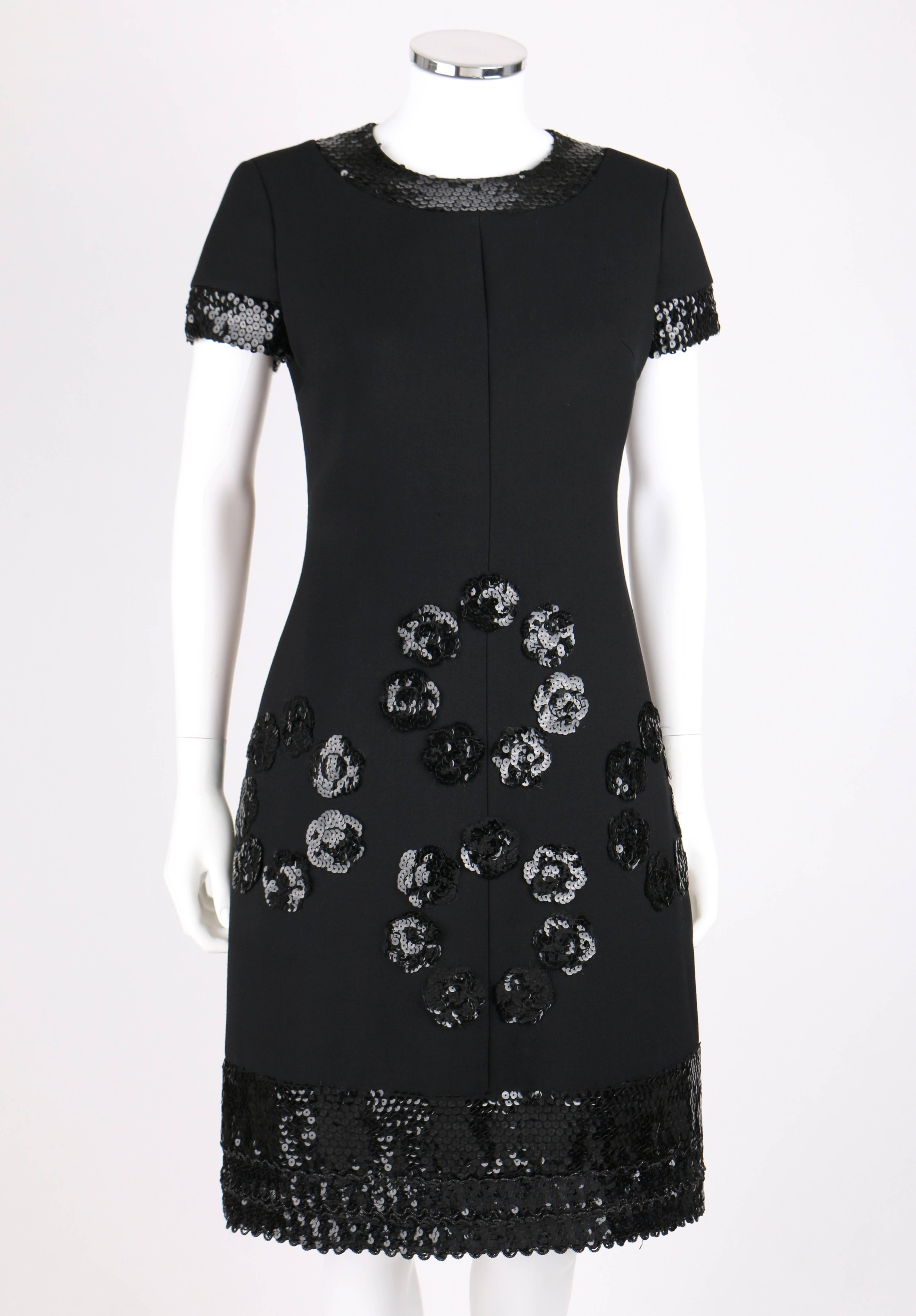 Vintage Jean Patou c.1960's black wool cocktail dress designed by Karl Lagerfeld. Short sleeves with scoop neckline. Black sequin trim along cuffs and collar with beaded scallop shaped hemline. Four clusters of sequin camellia flowers along front.
