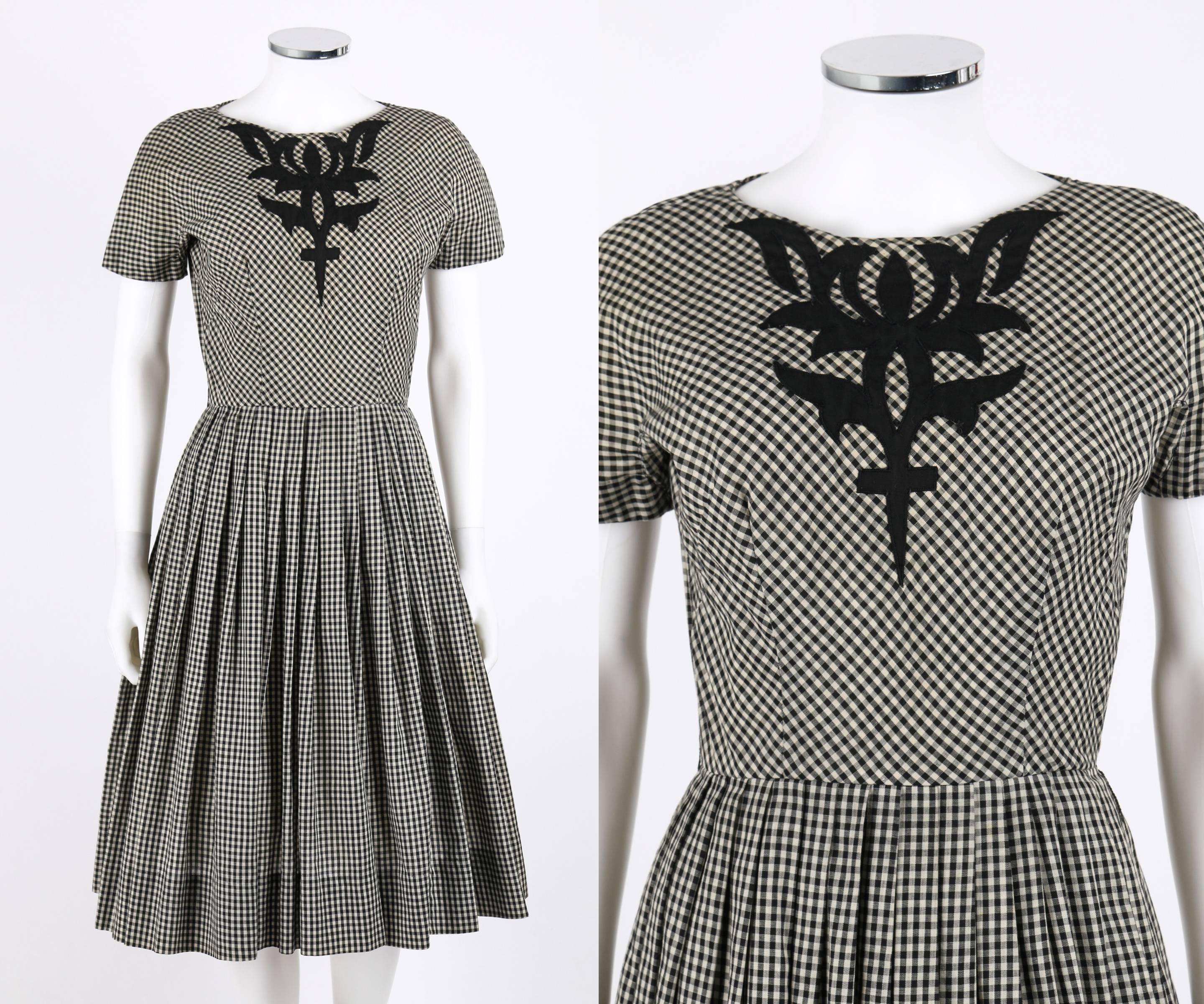 Vintage Jeanne Durrell (Lorch Co.) c.1950's black white gingham check day dress. Center front black avant garde applique. Short gusseted sleeves. Angled scoop neckline. Knife pleated skirt. Center back metal zipper with hook and bar closure at top.