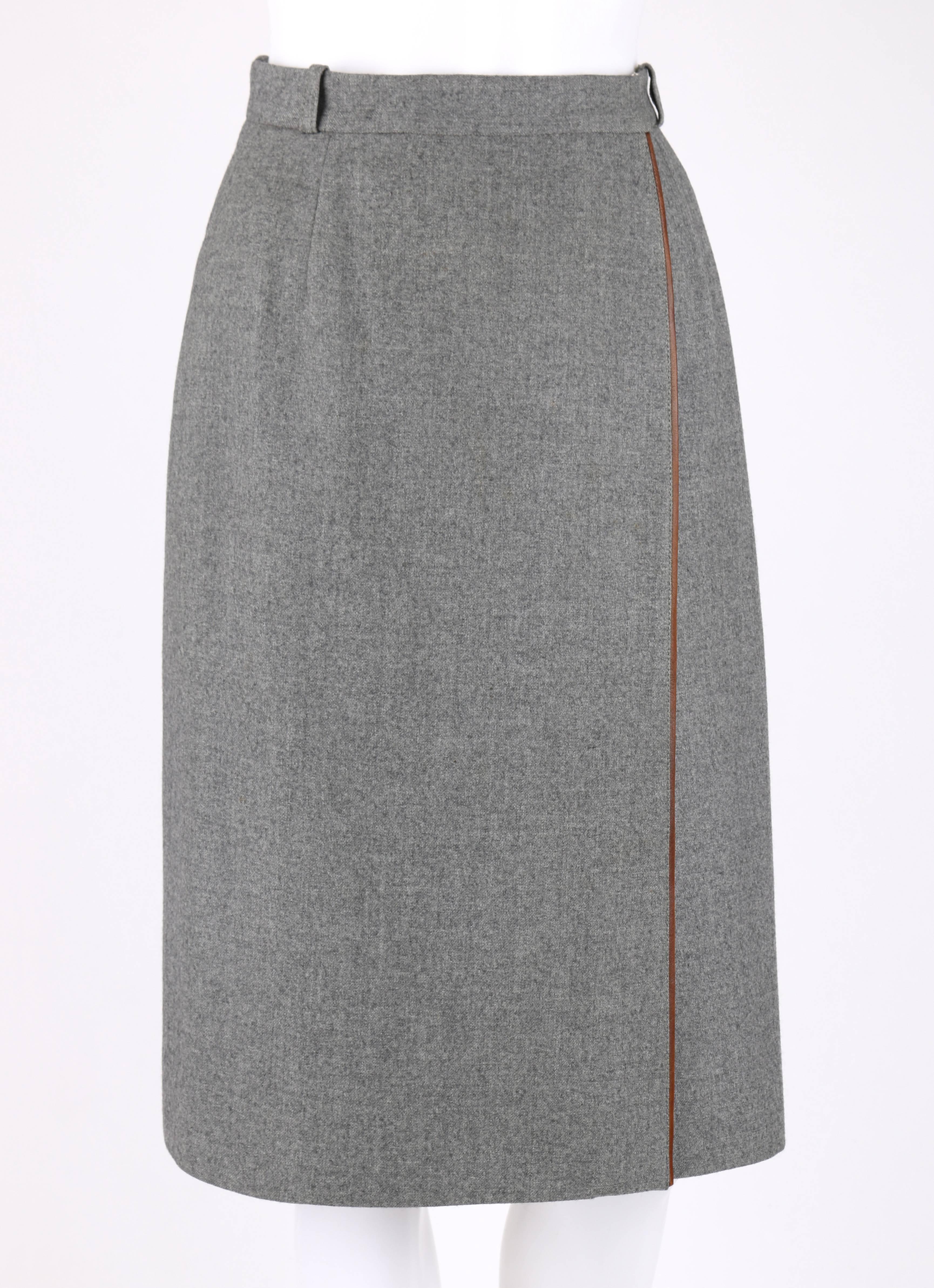 Vintage Gucci c.1970's gray wool wrap skirt. Four belt loops. Brown leather piping detail. Front wrap design with hook and bar and single button closures. Front and back waistline darts. Fully lined. Marked Fabric Content: 