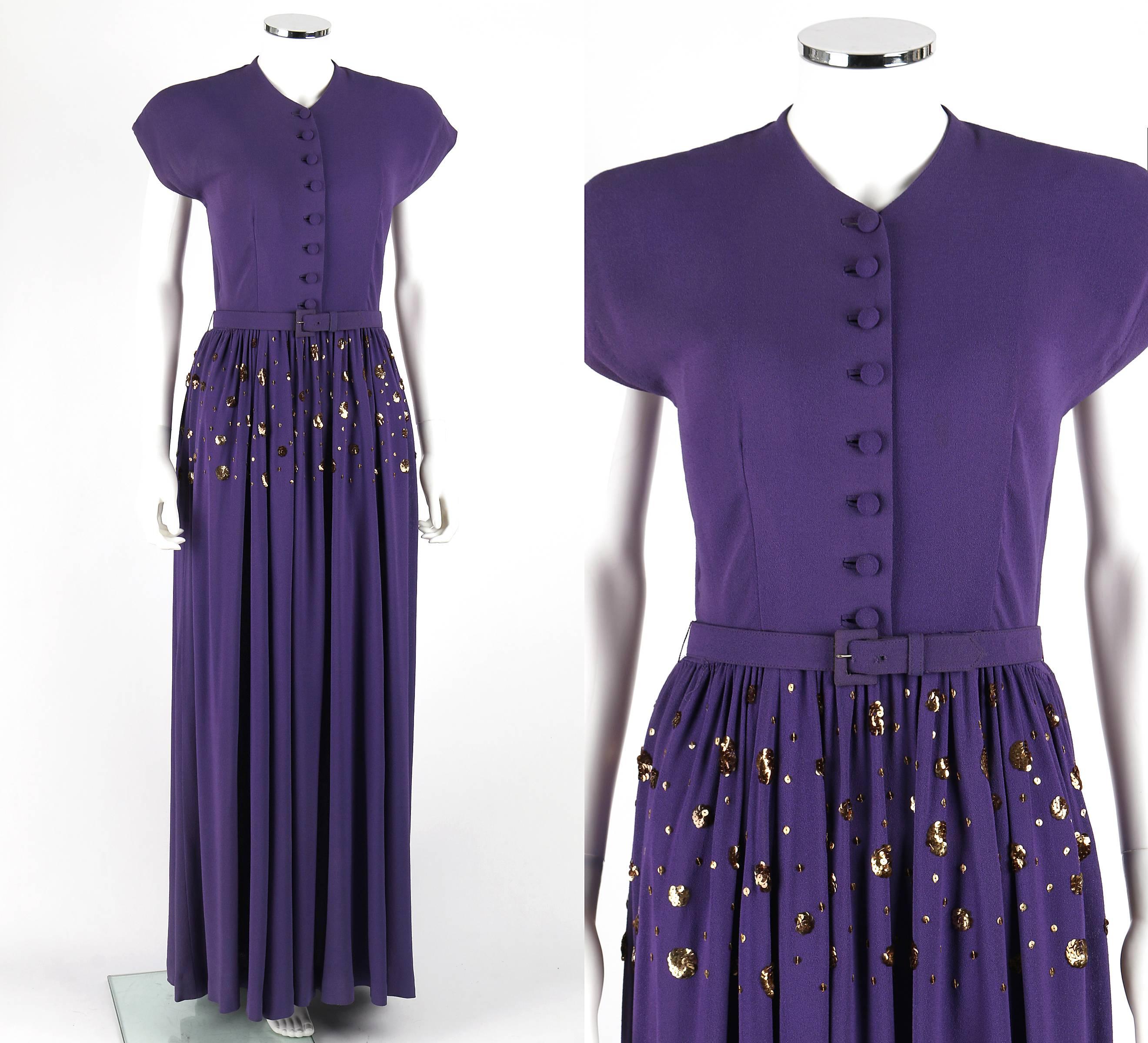 Vintage Couture c.1940's lila Knopf vorne bodenlanges Abendkleid. Verlängerte Schultern. Hoher V-Ausschnitt. Acht verdeckte Kuppelknöpfe in der vorderen Mitte. Goldfarbene Pailletten-Verzierung an der Hüfte. Geraffter Rock. Metallreißverschluss an