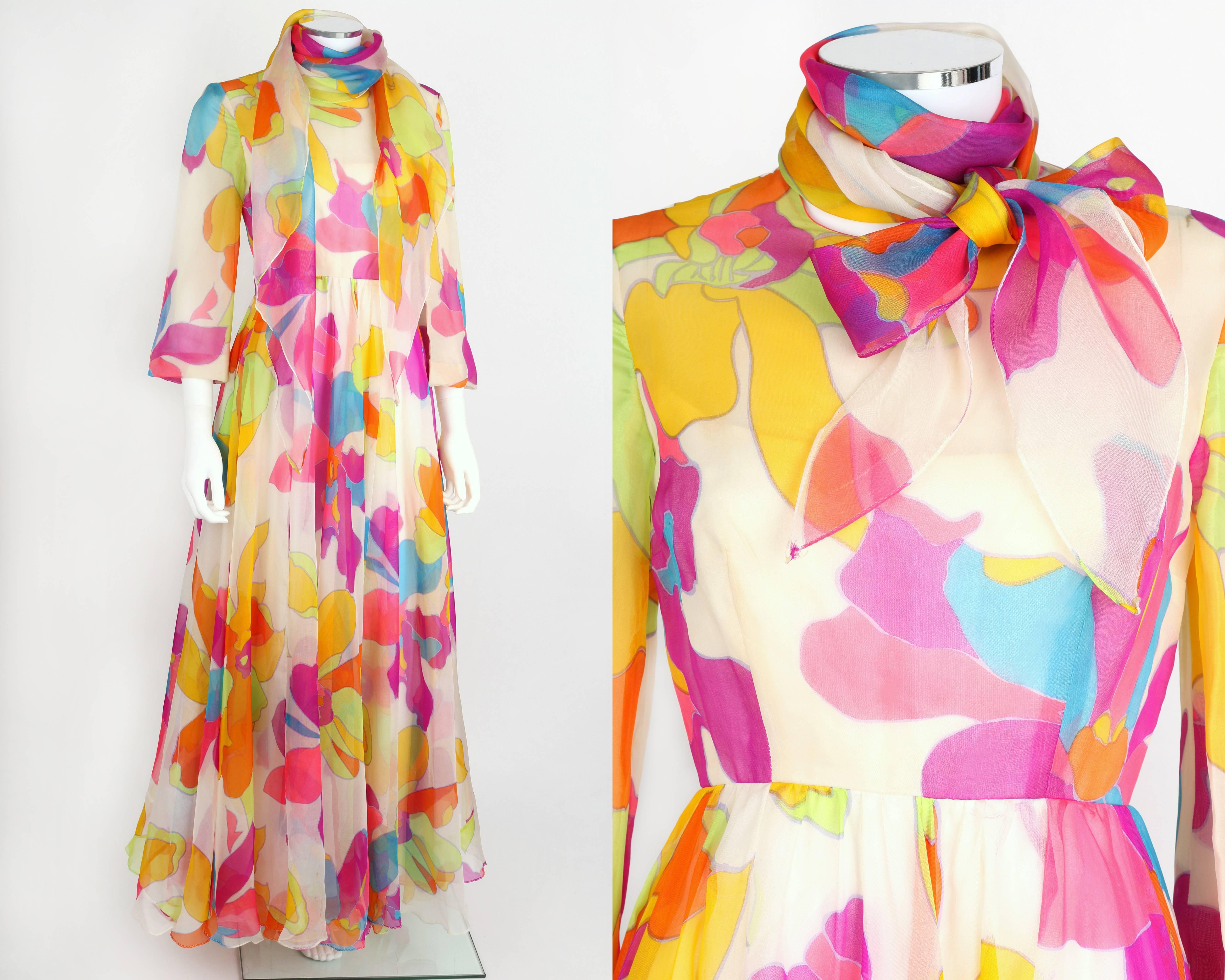 Vintage Kiki Hart c.1970's white chiffon maxi dress with a brightly colored psychedelic floral print in shades of hot pink, orange, lime green, blue, and magenta. 3/4 length sleeves. Crew neckline. Attached scarf with angled tails at back of
