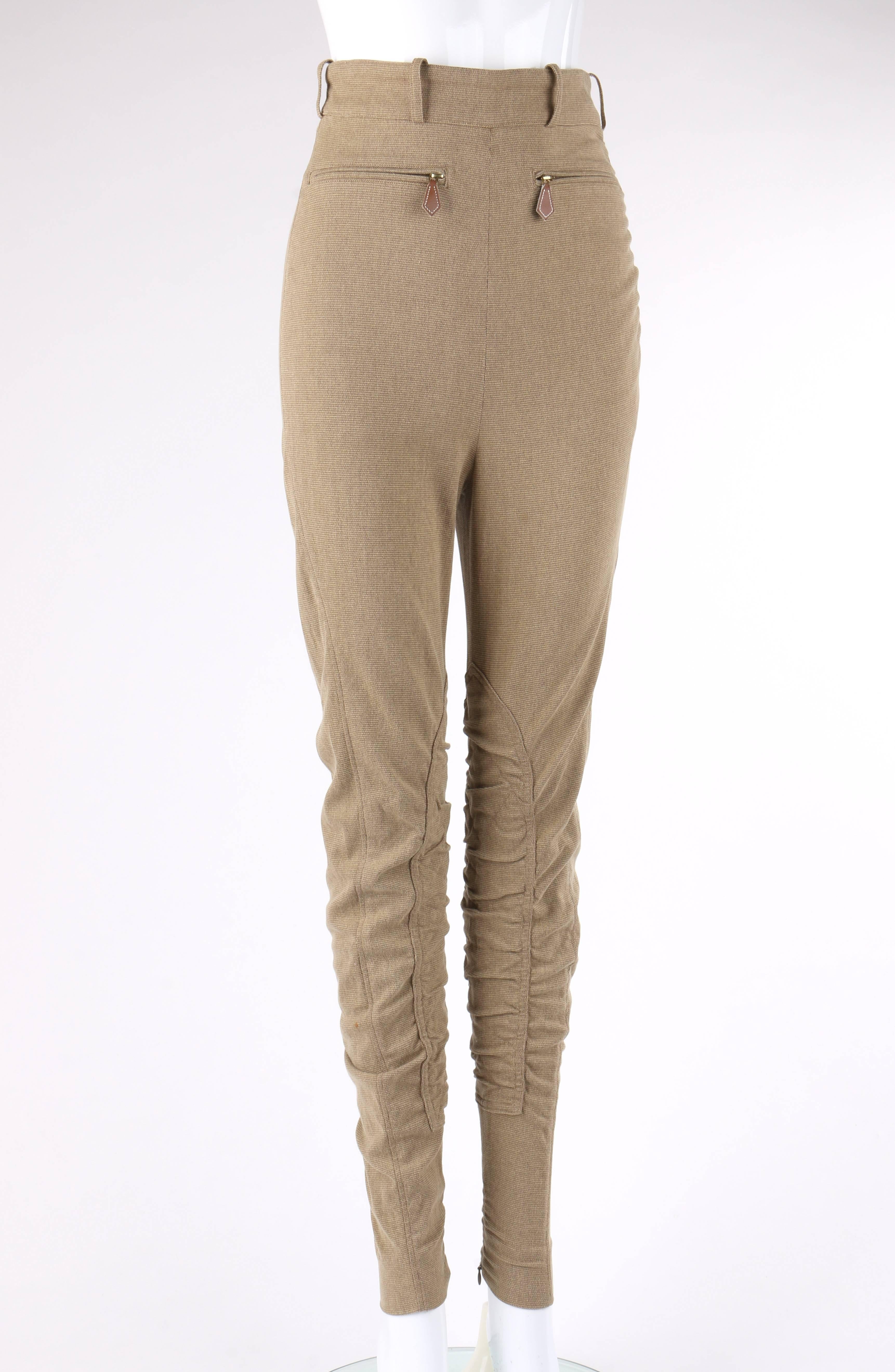Jodhpurs d'équitation Hermès datant des années 1990:: de couleur kaki et à taille haute. Mélange de coton extensible. Taille haute avec bande et sept passants de ceinture. Deux pinces à la taille dans le dos. Fermeture à glissière invisible sur le