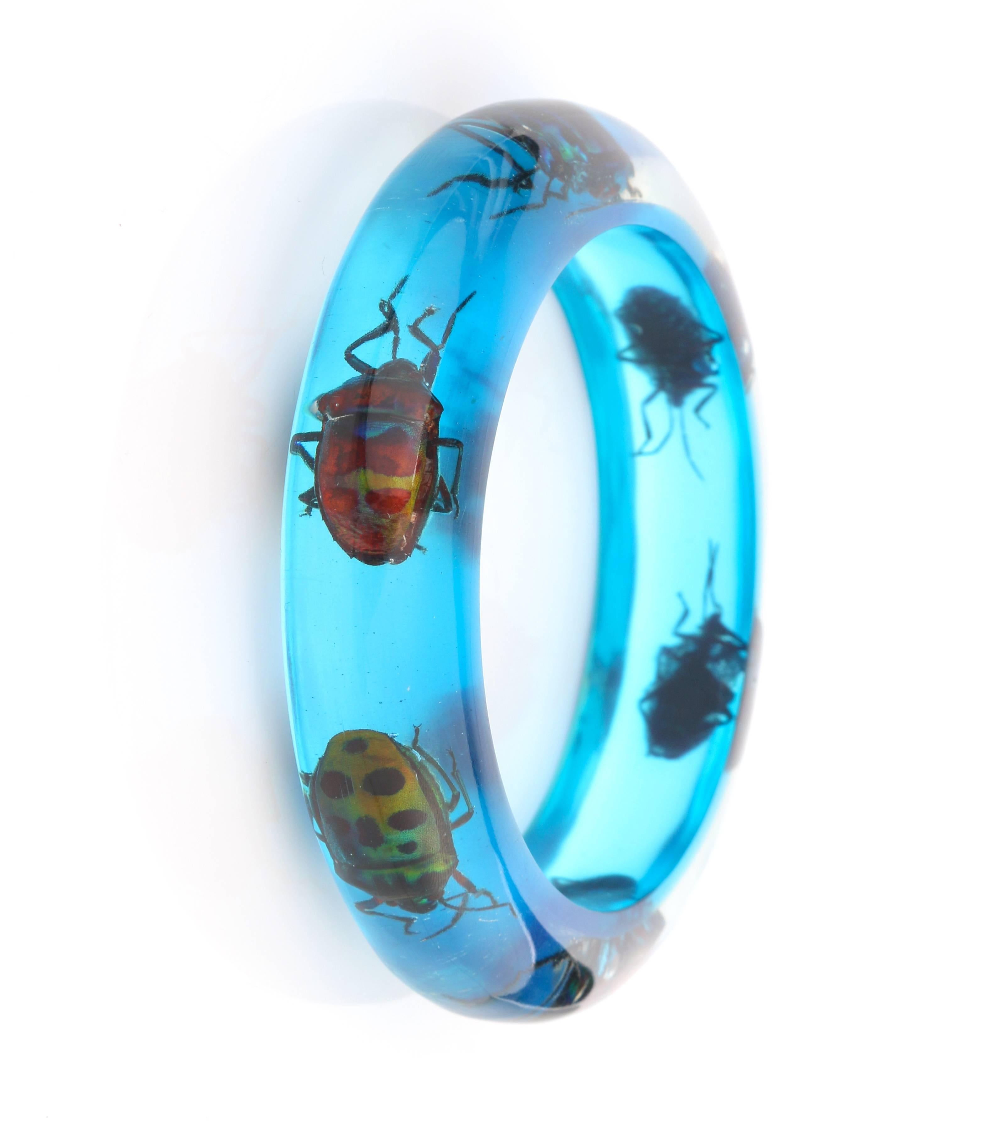 Vintage mid-century blue translucent lucite iridescent beetle embedded bangle bracelet. Six multicolored iridescent exotic beetles embedded in translucent blue lucite. Circular shape. Slip-on style. Marked 
