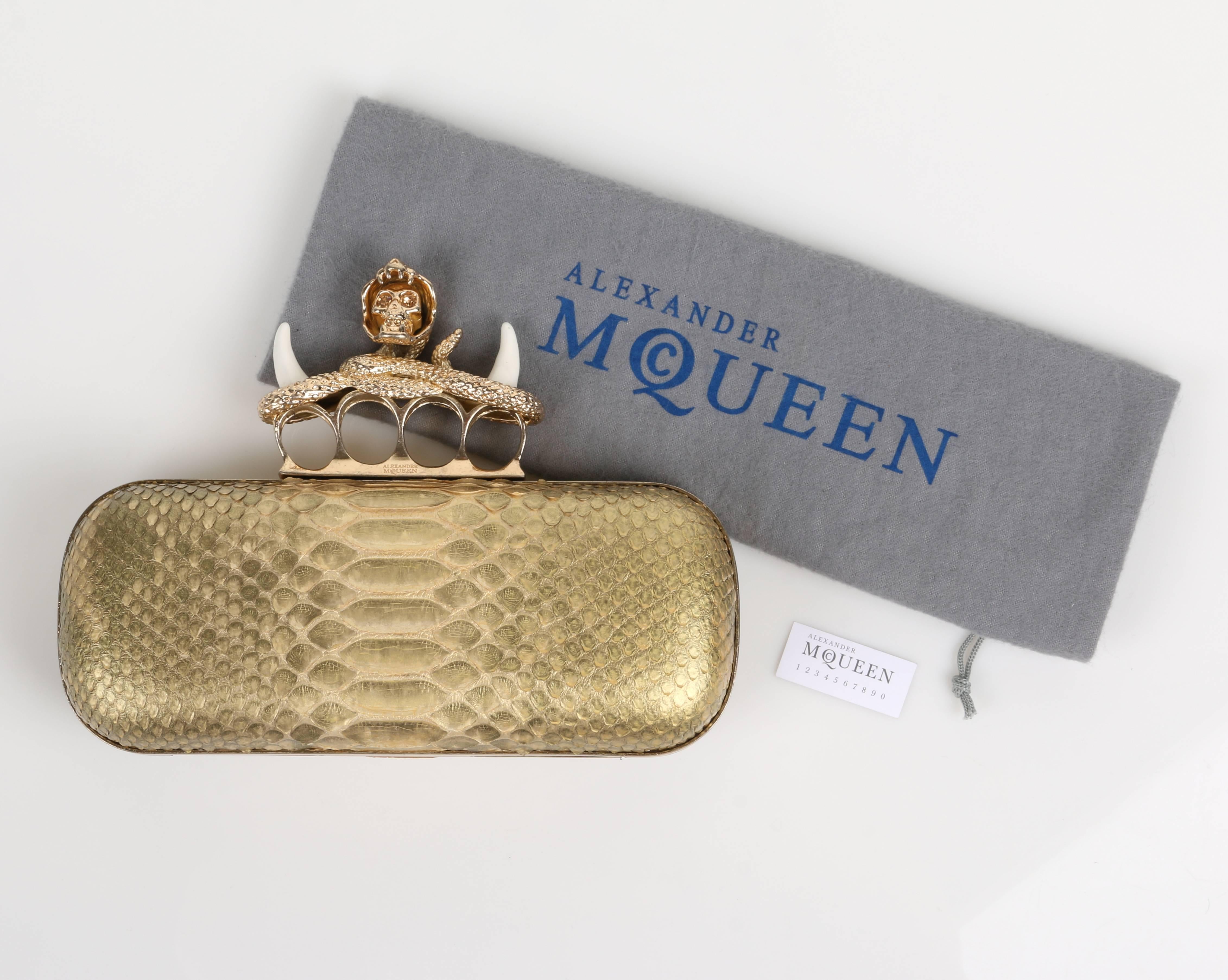 Alexander McQueen c.2012 gold genuine python knuckle-duster clutch. Distressed gold-tone hardware. Signature hinged clasp with four "rings" embellished with rhinestone detail featuring a snake, skull, and enamel fangs. Framed rectangular