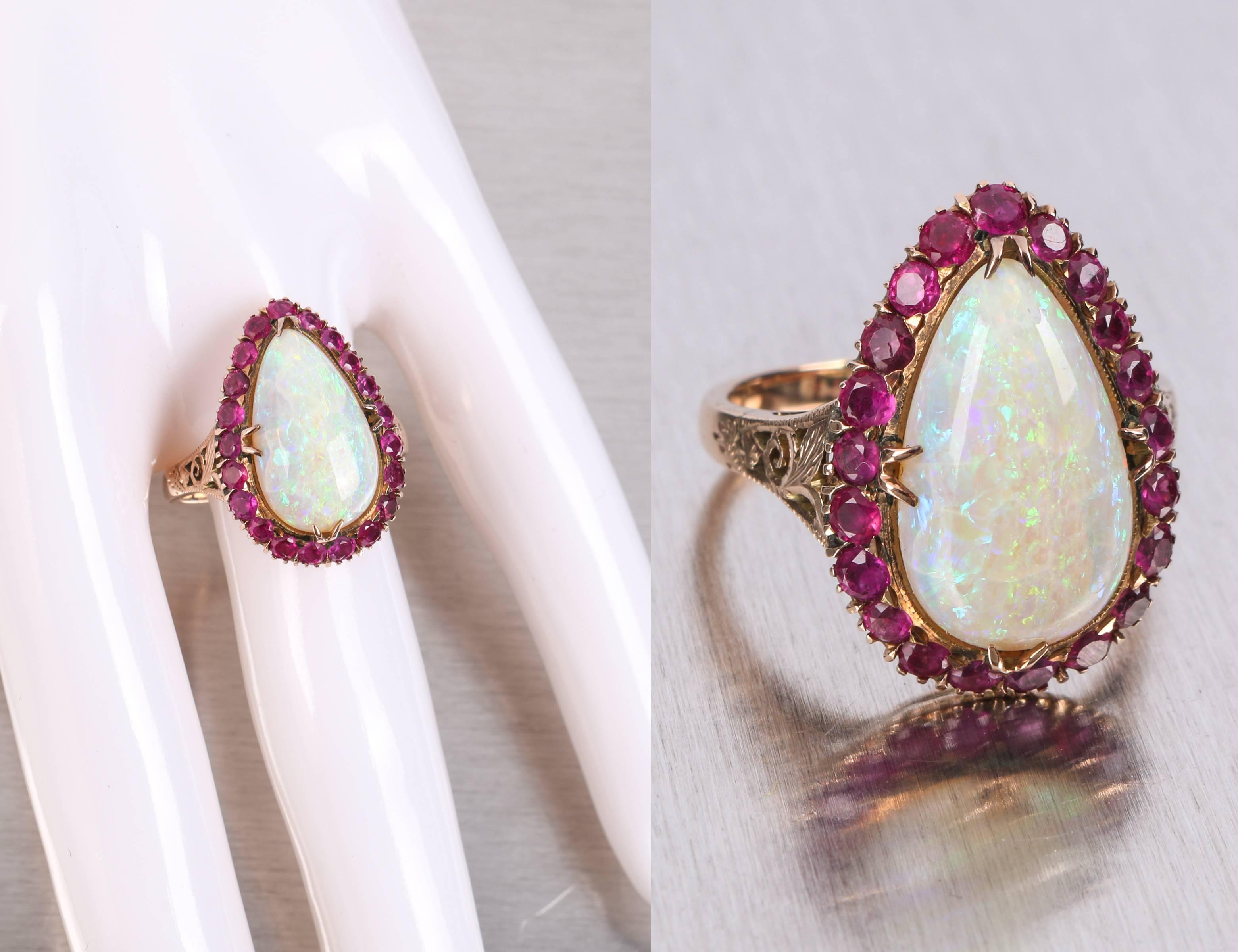 Vintage c.1930-1940's rose gold 14 kt large teardrop opal ruby ring. High polish rose gold mounting has open scroll work on either side of pronged setting. Main stone is a large cabochon cut, prong set, teardrop opal. Opal has reds, blue and green