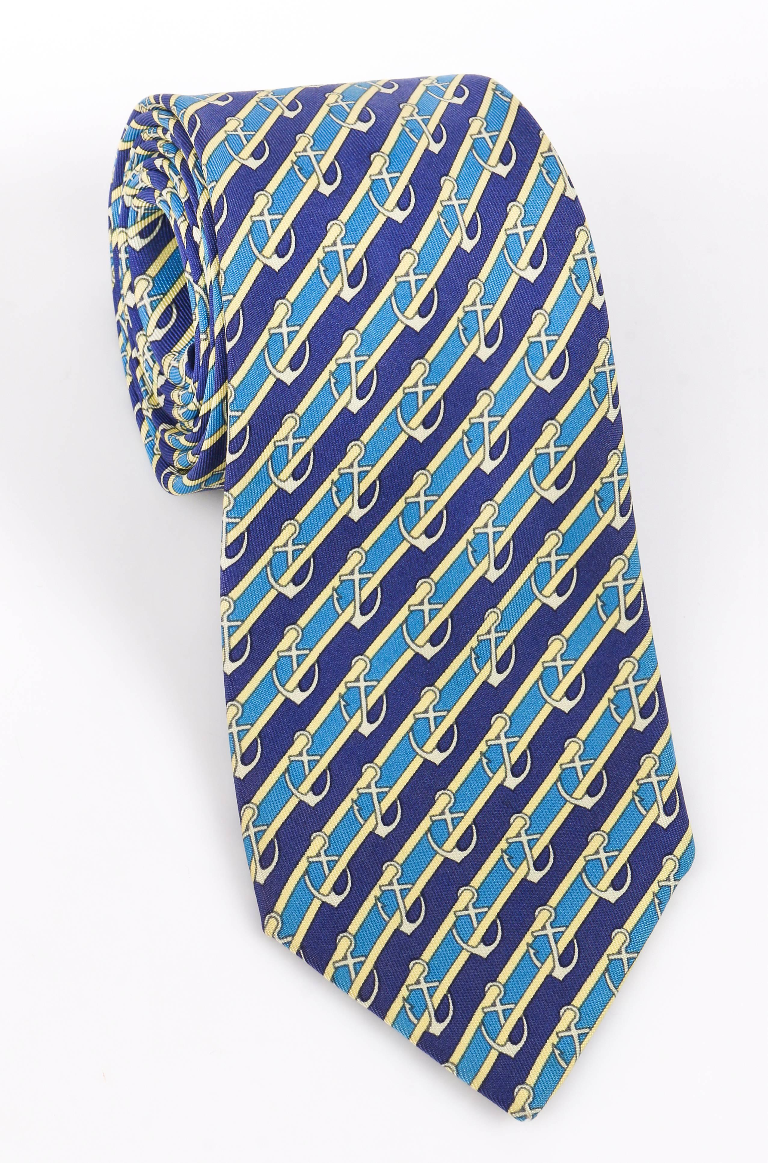 Hermes navy, blue, and yellow stripped neck tie with nautical anchors. Hermes logo printed on neck tie tail. 5 fold. Serial number 7027 TA. Marked Fabric Content: 