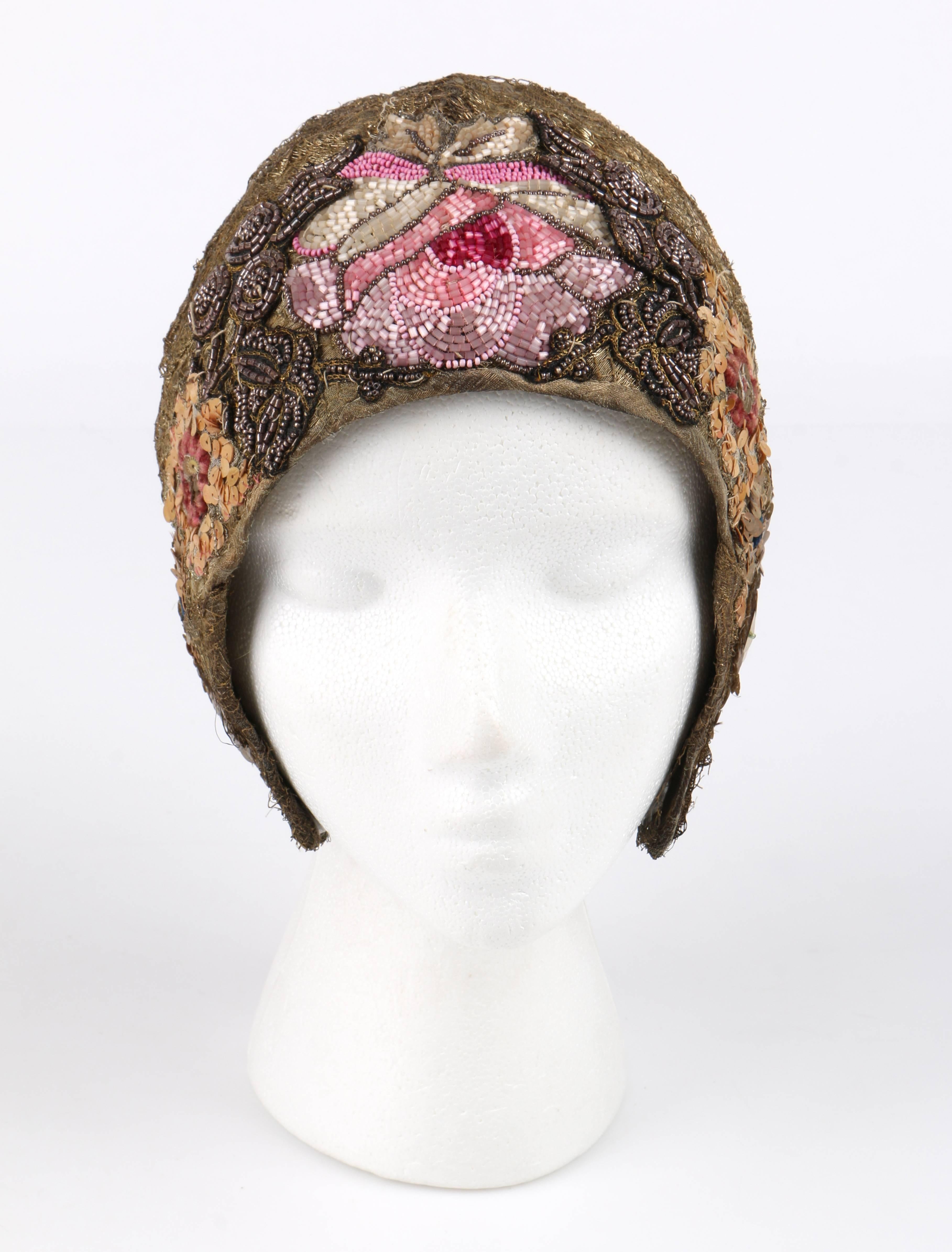 Vintage c.1920's Mannheimer gold lace floral embellished helmut style flapper cloche evening hat. Metallic bullion gold chantilly lace body. Multicolored hand glass beaded and sequin floral embellishment around temple and front. Three darts at back.