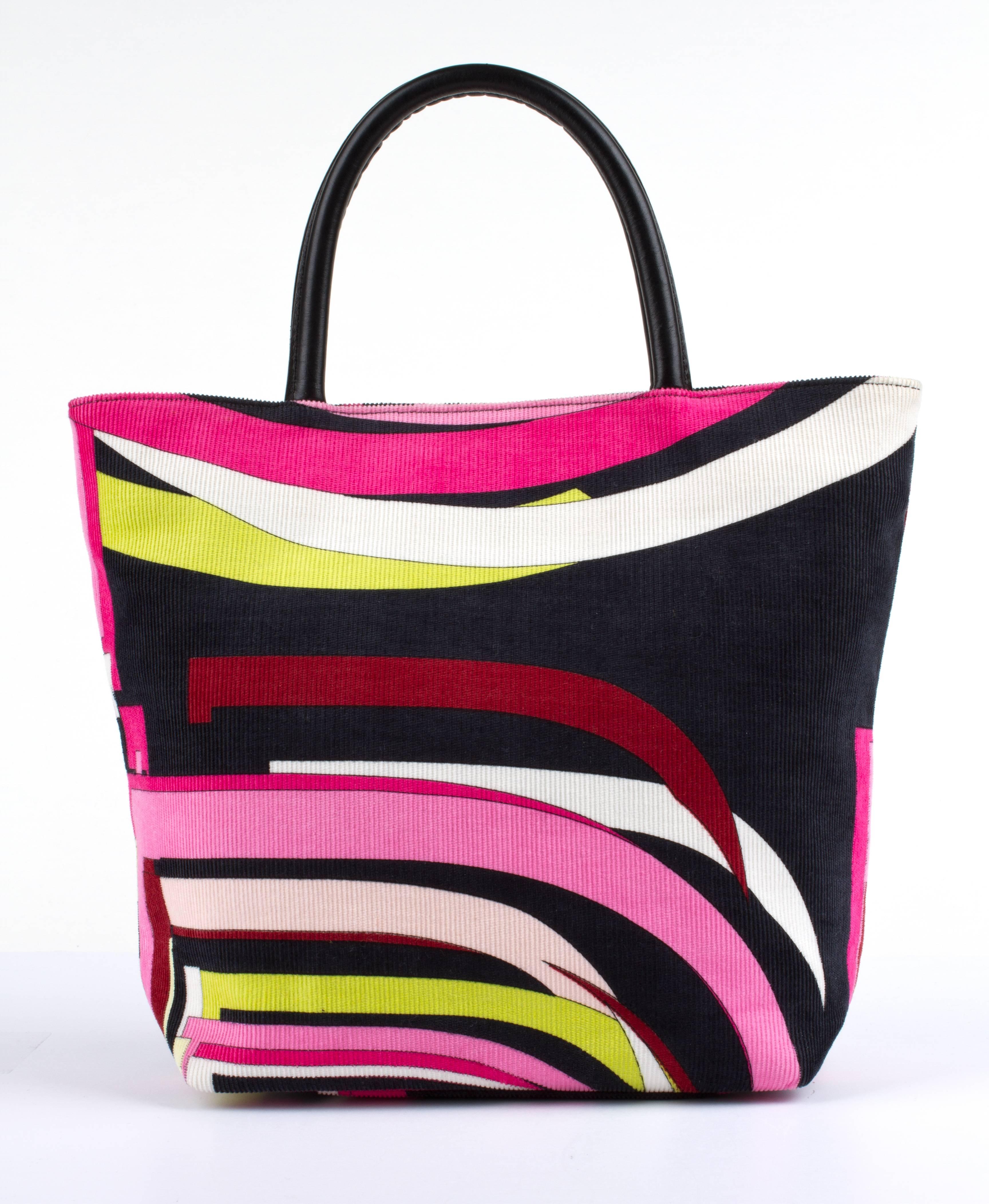 Emilio Pucci multi-color signature print corduroy handbag. Geometric op-art print fabric. Dual flat black leather feet and rolled top handles. Black synthetic lining with interior zip pocket and magnetic snap closure. 