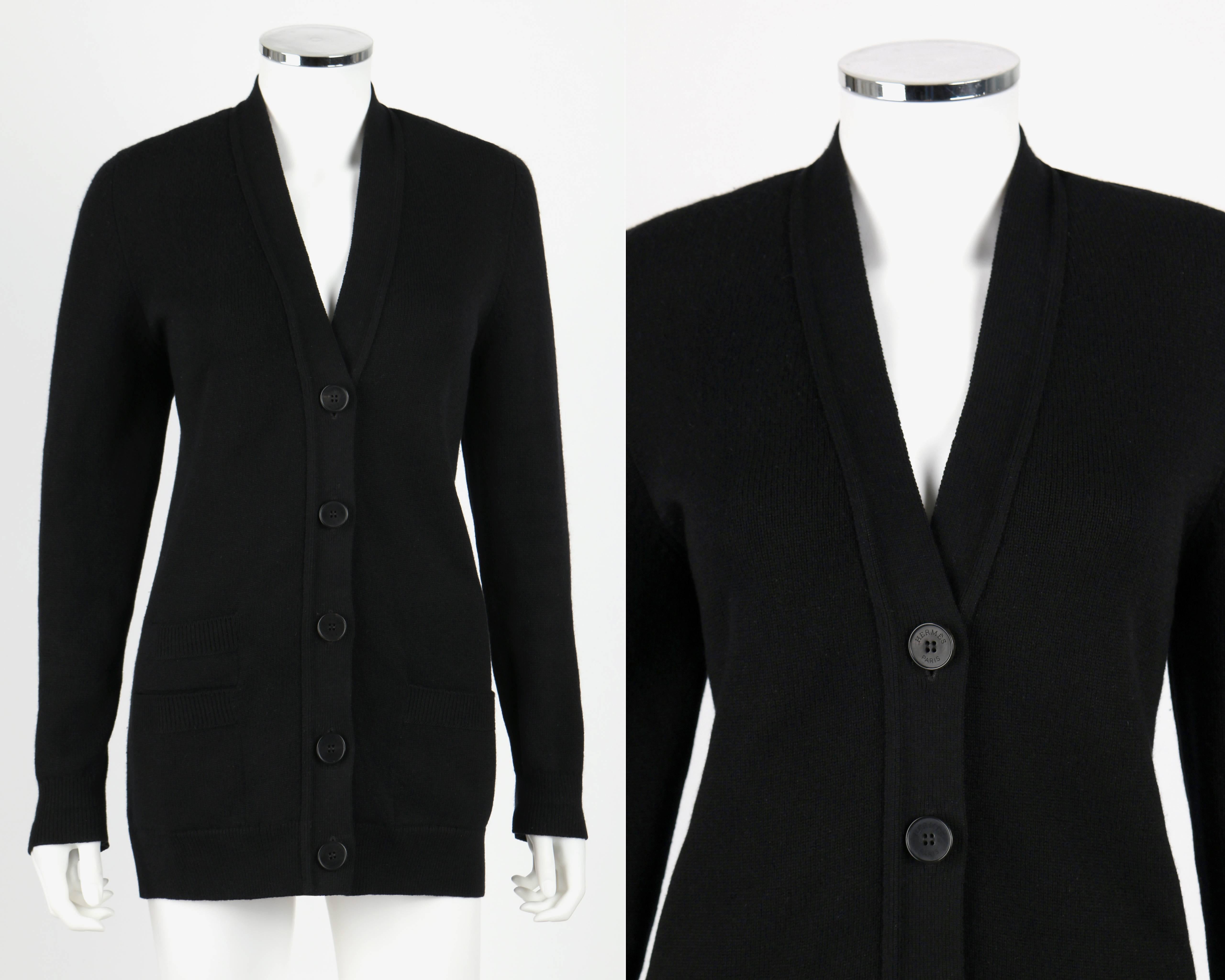 Hermes long black 100% cashmere cardigan sweater. V-neckline. Five button front closure. Three inset pockets: One on the front left side, two stacked on the right. Rib knit detail along hem, cuffs and pockets. Buttons embossed with signature