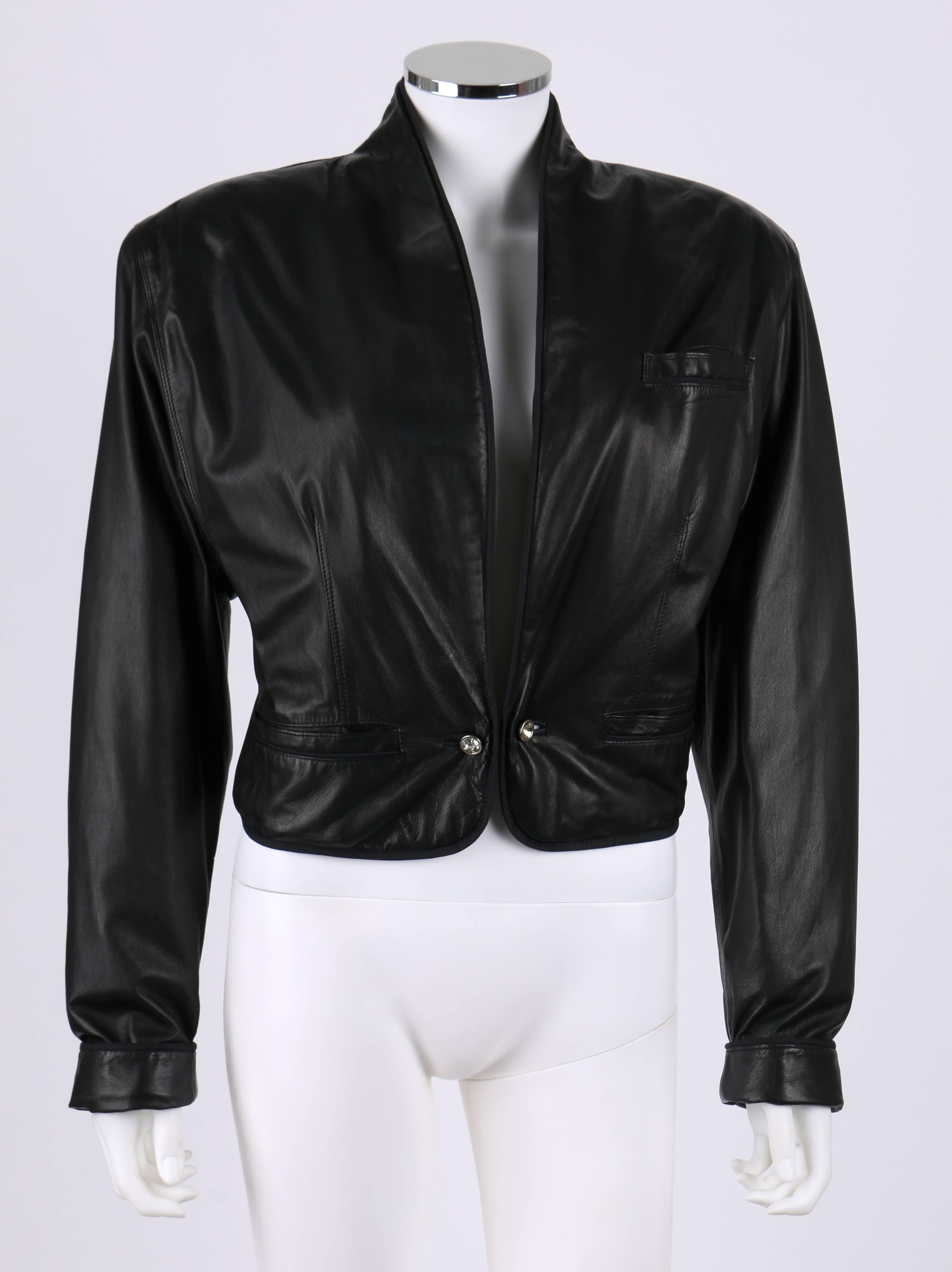 Gianni Versace c.1980's black leather cropped blazer jacket. Shoulder pads. Shawl collar. Silver-tone chain and rhinestone toggle closure. Fold over cuffs with rhinestone toggle fasteners. Two shallow single welt pockets adjacent to front closure.