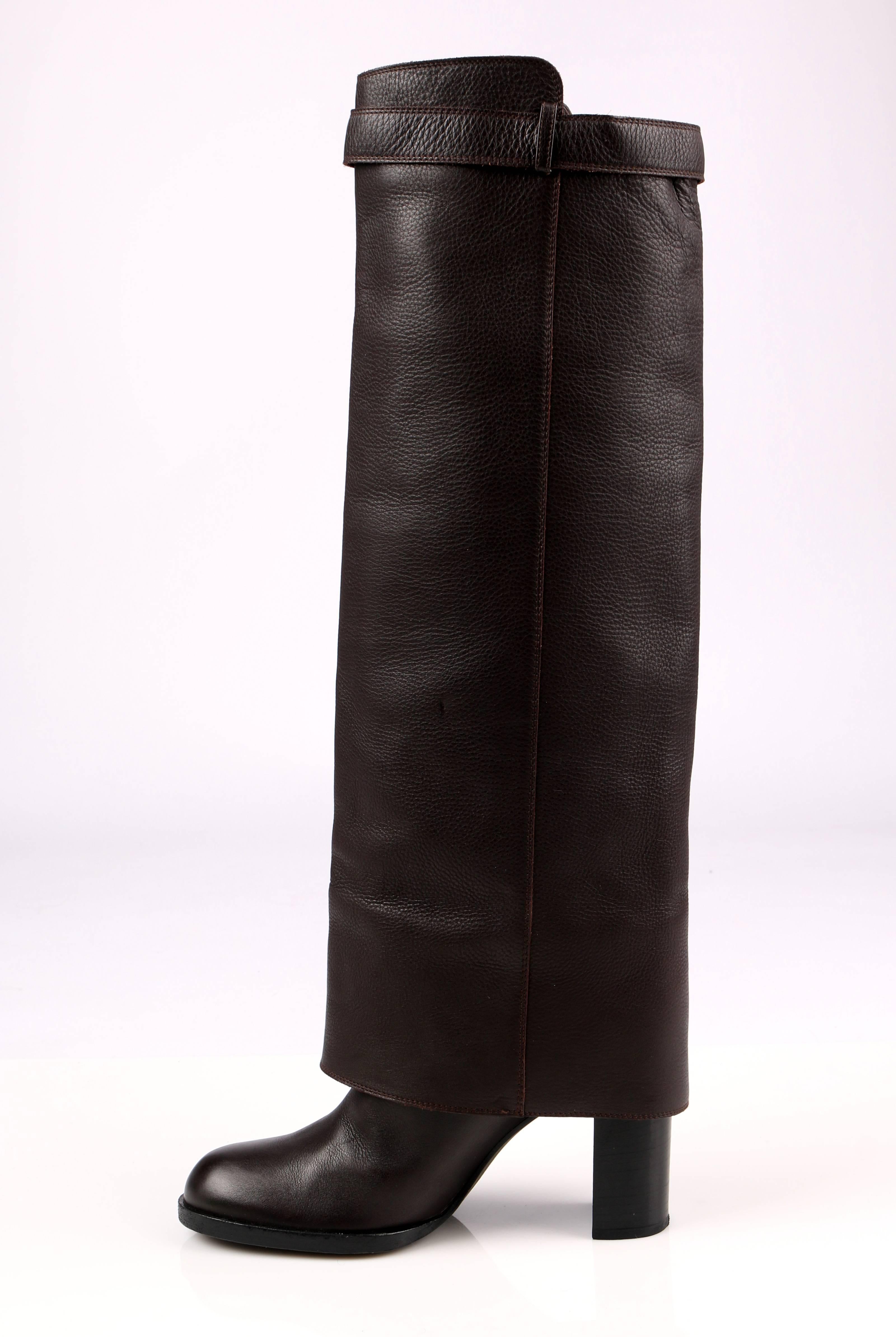 Chanel dark brown leather knee high boots. Fold-over panel with adjustable strap. Silver-tone embossed signature 