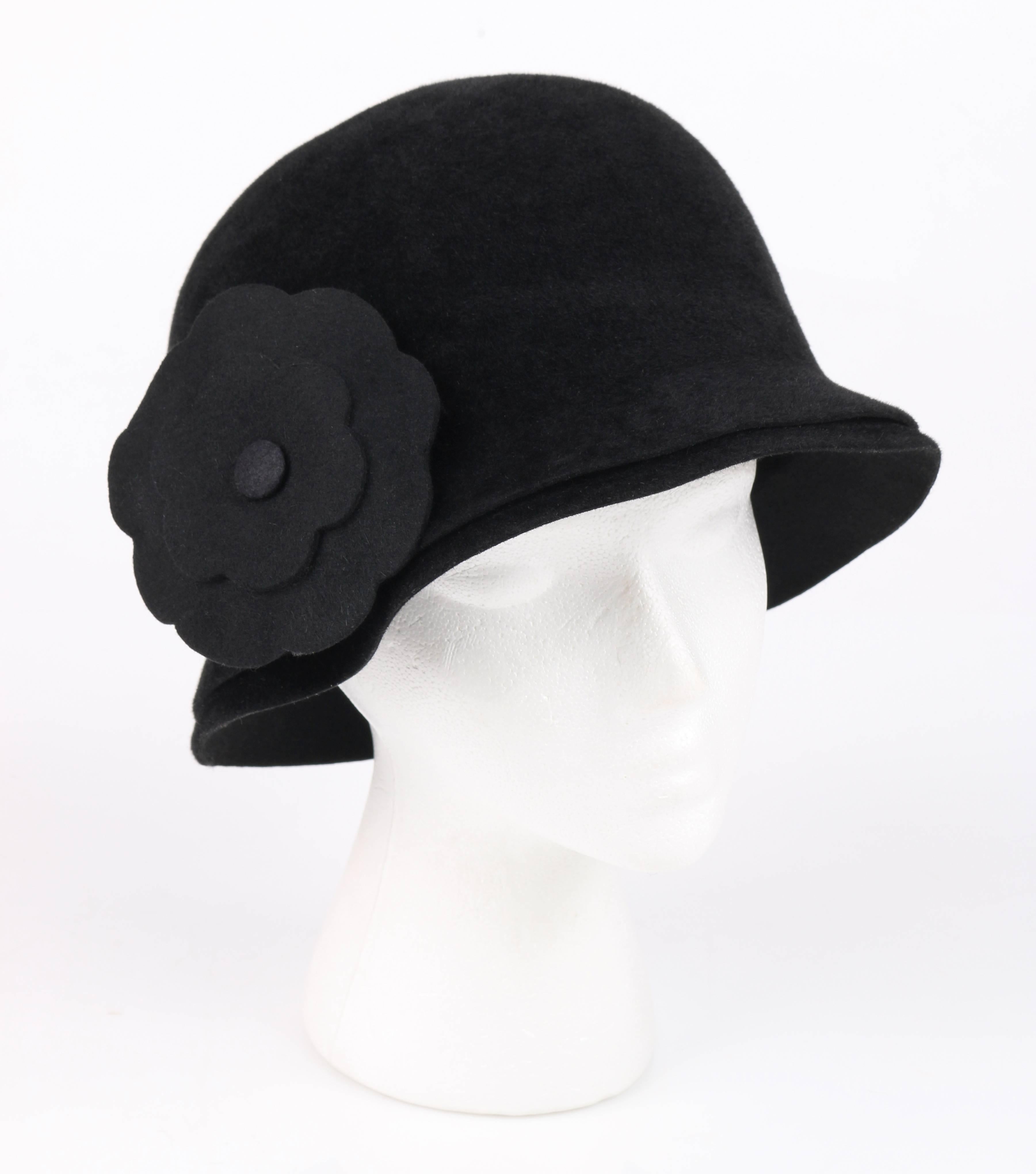 Chanel A/W 1998 black fur felt cloche style hat. Fur felt bell shaped body. Double brim. Black gross grain ribbon along interior edge. Unlined. Matching camellia flower removable brooch. Black stem with gold-toned needle clasp closure. Gold tag