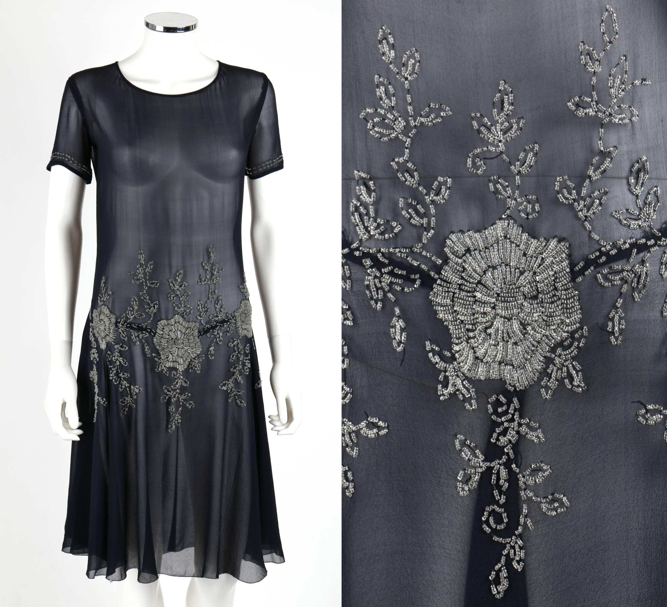 Vintage Couture (one of a kind) c.1920's navy chiffon evening dress. Short sleeves. Scoop neckline. Drop waist. Bias cut skirt. Clear glass bead floral embellishment at waistline and cuffs. Unmarked Fabric Content: Silk, glass beads. Measurements: