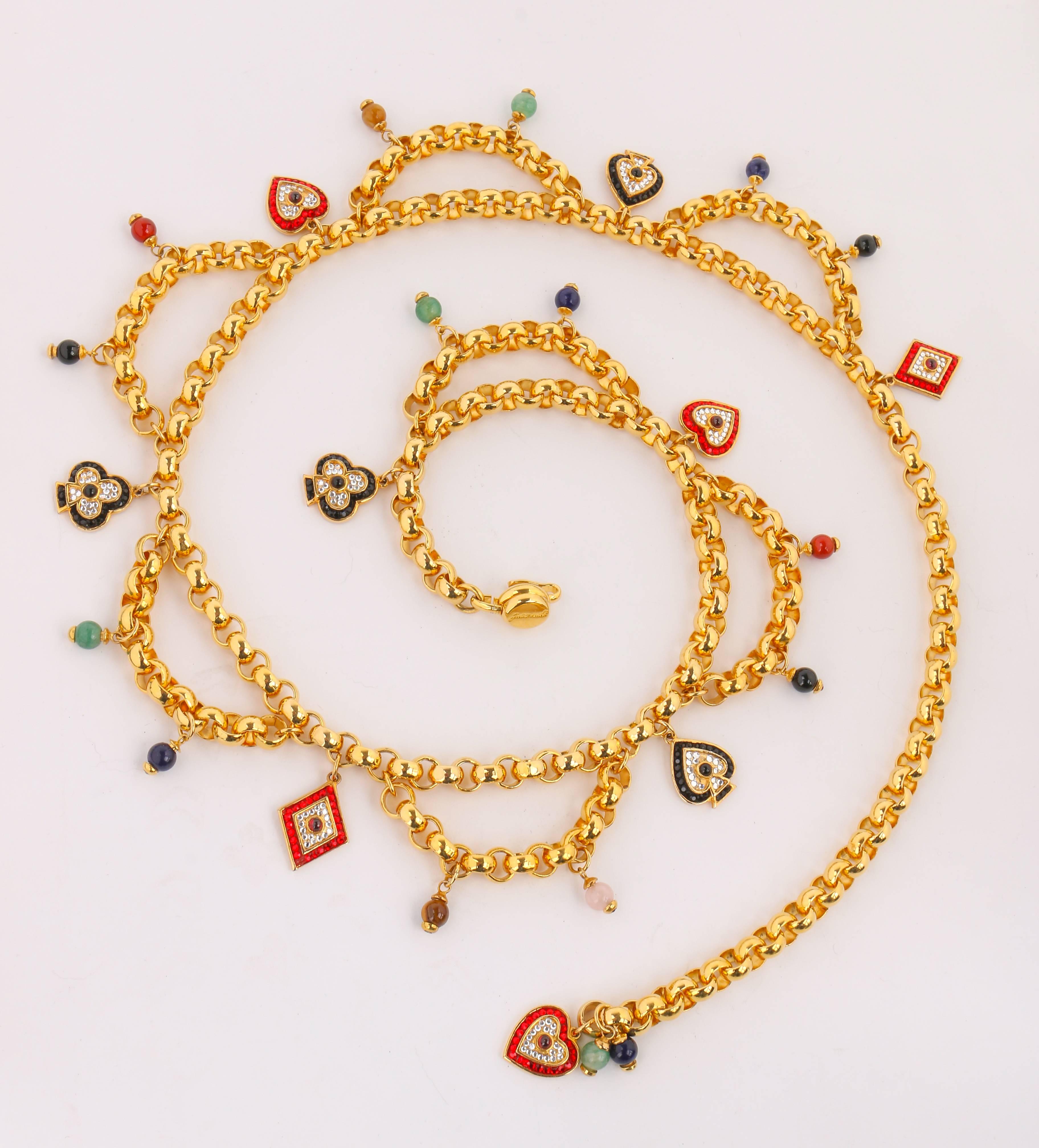 Judith Leiber gold-toned card suit charm chain belt. Gold-toned rolo chain with  rhinestone embellished heart, club, diamond, and spade charms. Draped chain sections with round multicolor stone bead charms. J hook clasp for adjustable fit. Marked: