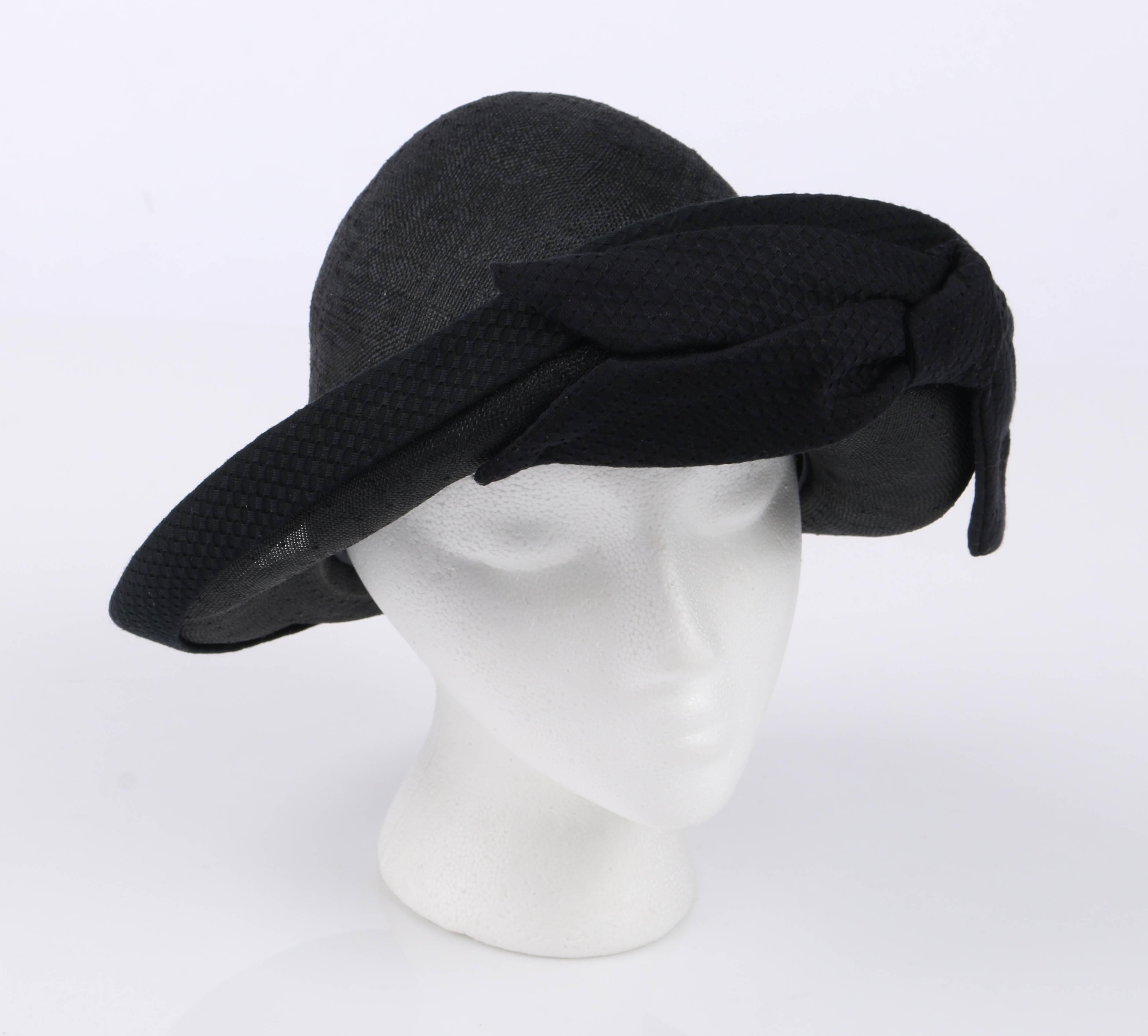 Oscar De La Renta Millinery black woven straw vegabond style hat. Asymmetrical turned up brim. Side front abstract bow. Textured cotton fabric detail around edge of brim, hat band, and bow. Black grosgrain ribbon along interior edge. Unmarked Fabric