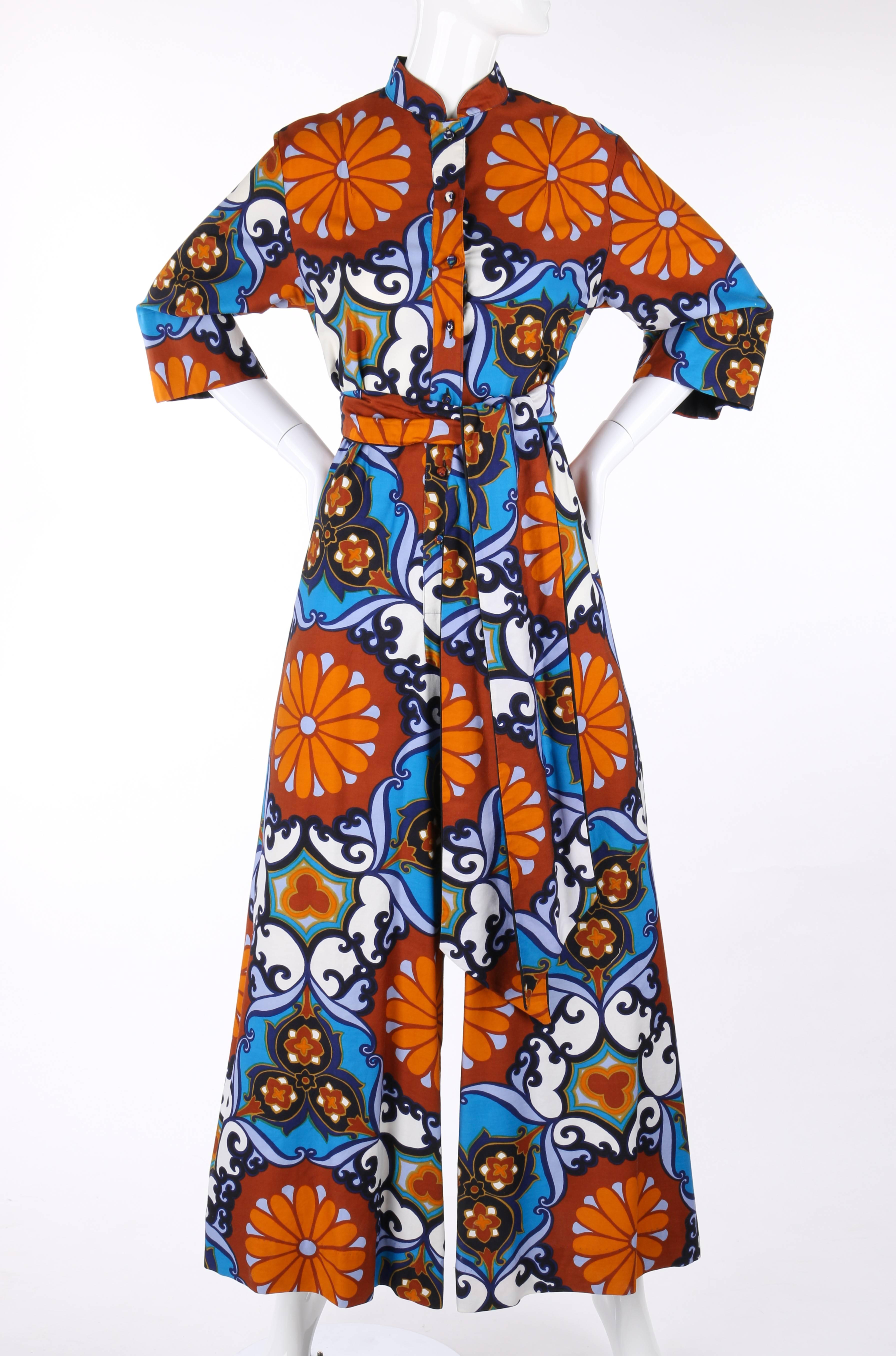 Vintage Penthouse Gallery c.1970's floral print palazzo jumpsuit designed by Catherine Ogust. Multi-color floral print cotton in shades of brown, orange, blue, green, and white. Mandarin collar. Seven center front button closures. Matching fabric