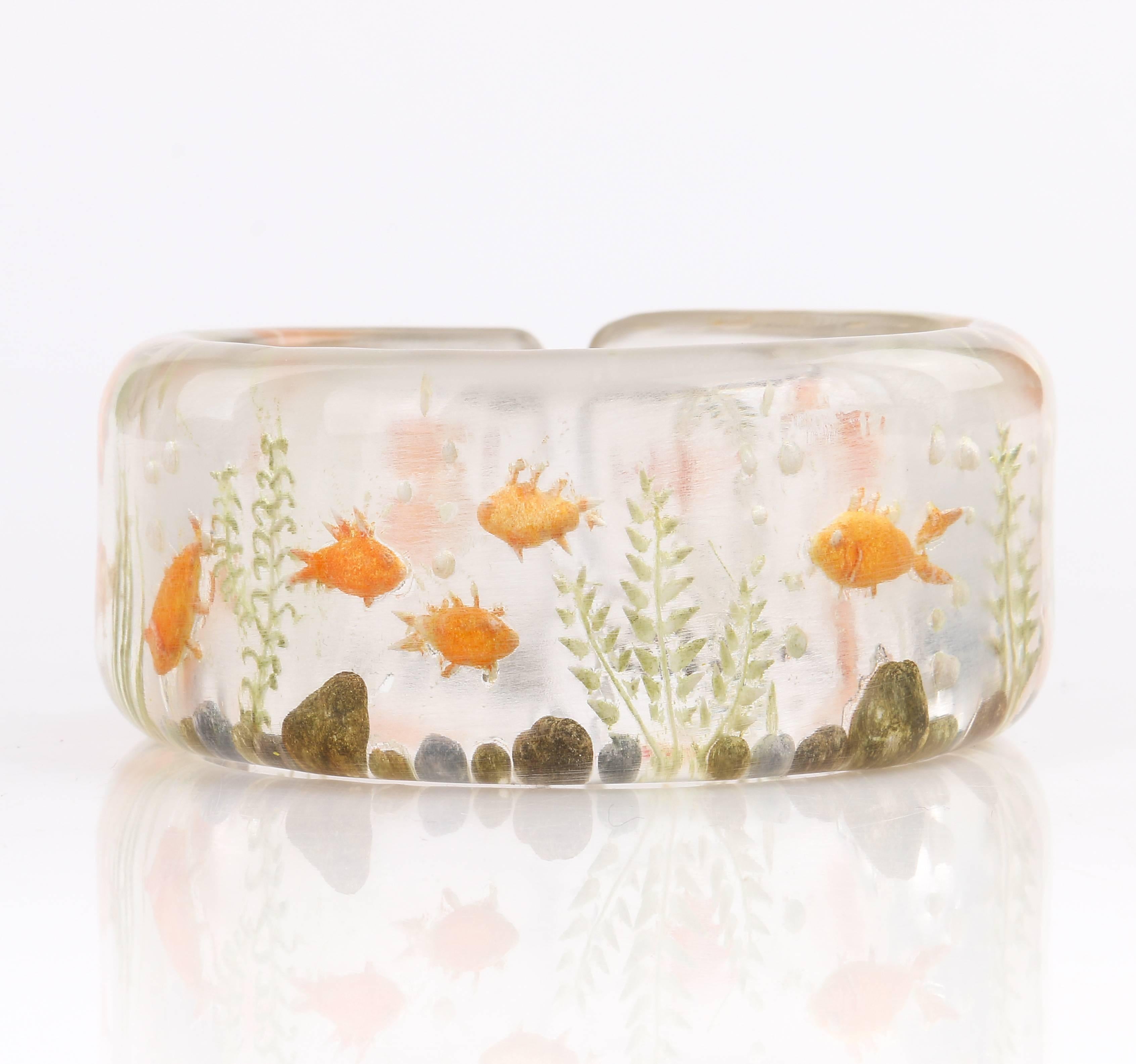 Vintage c.1940's clear plastic lucite reversed hand carved bracelet. Reverse hand carved underwater motif of goldfish, rocks, and seaweed. Smooth beveled edges. Small cuff opening. Unmarked Material: Plastic material. Measurements:

Inner