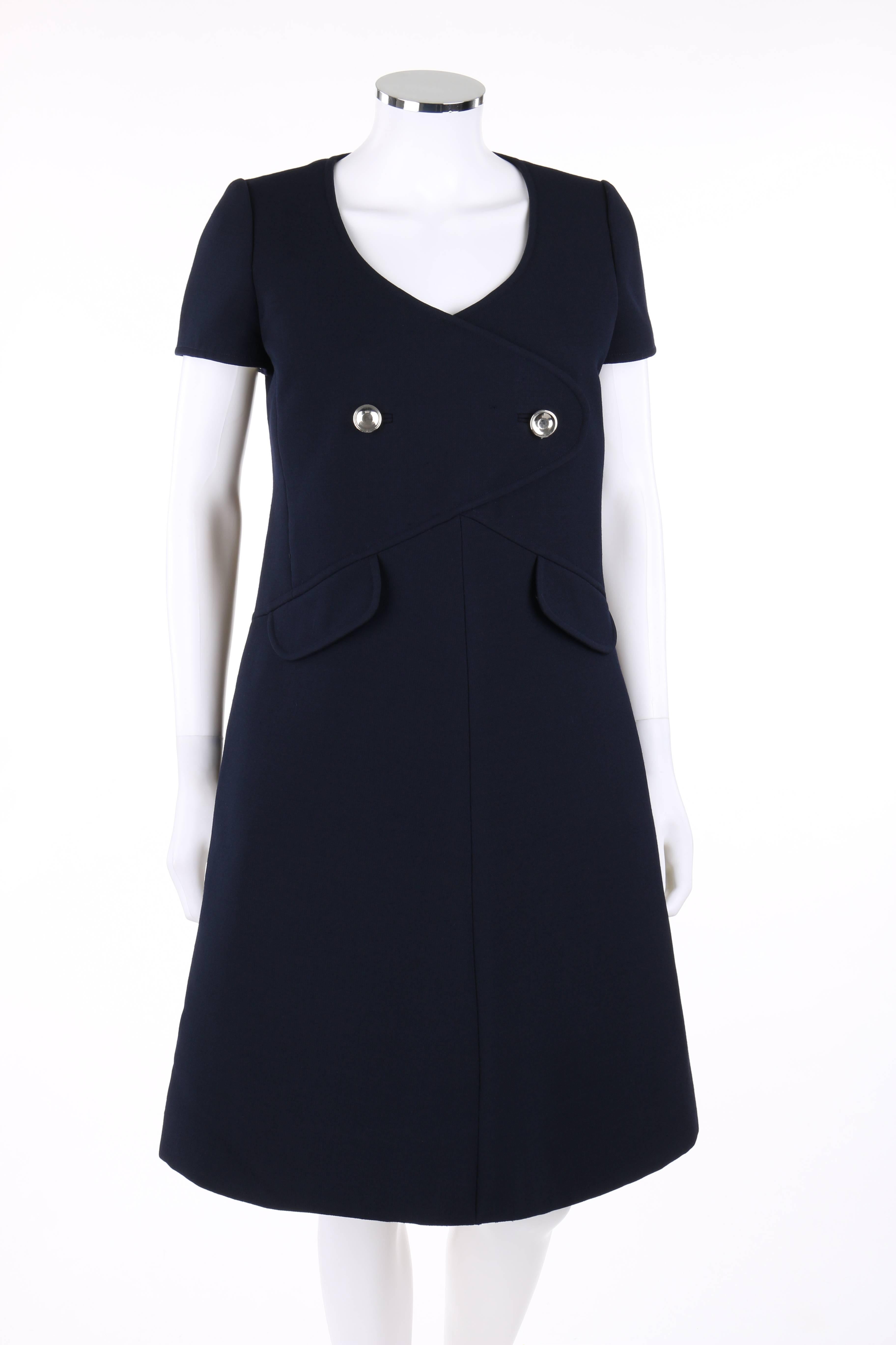 Vintage Courreges Paris for Bonwit Teller c.1960's navy blue wool a-line dress. Short sleeves. Scoop neckline. Princess seamed bodice. Faux wrap front detail with two round silver buttons. Two front mock flap pockets. Center back invisible zipper