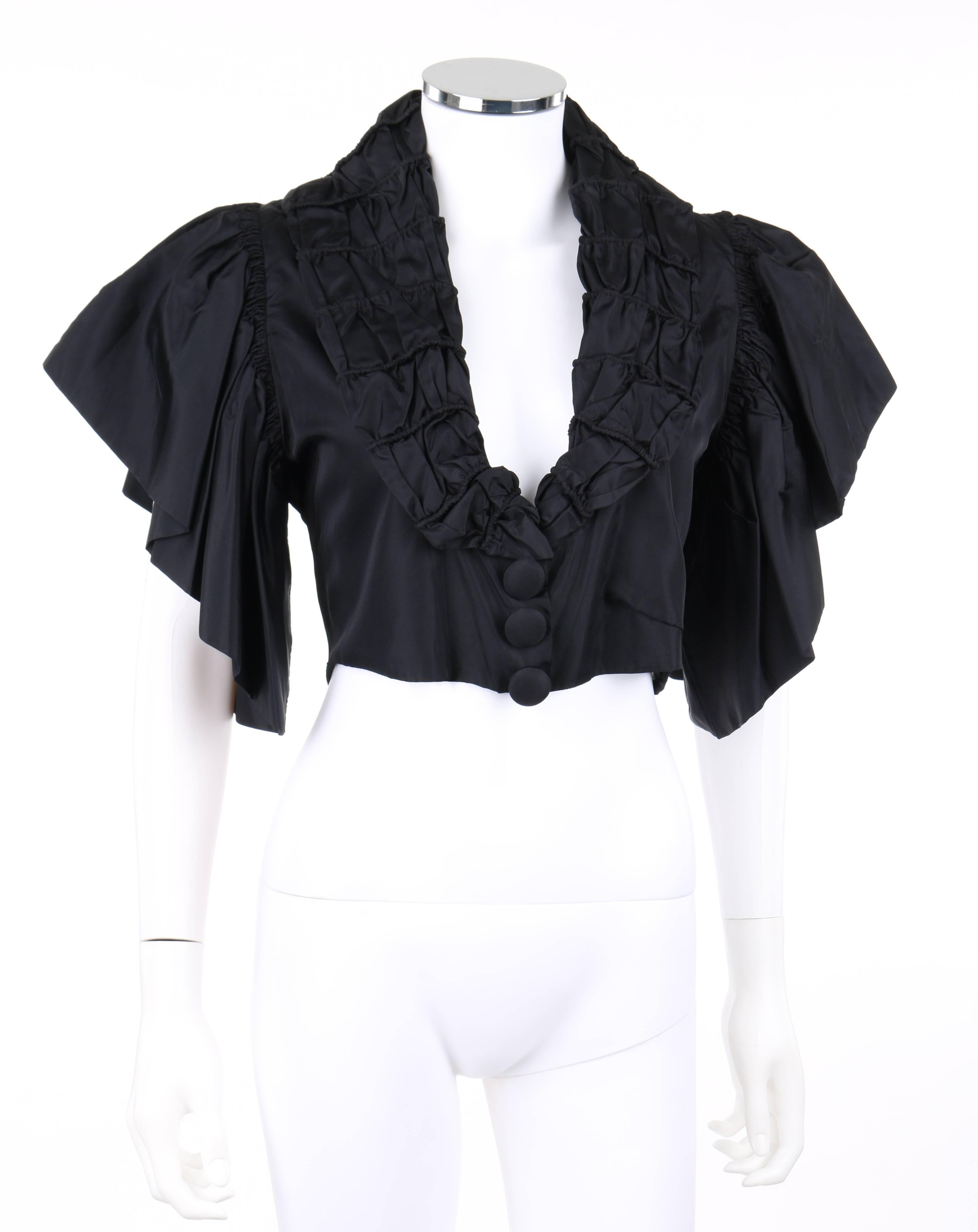 Vintage Jean Patou Adaptation c.1930's black silk capelet. Shawl collar with gathered piping detail. Three center front covered buttons over top snap closures. Short ruffled flounce sleeves. Center back vertical piping detail. Fully lined. Unmarked