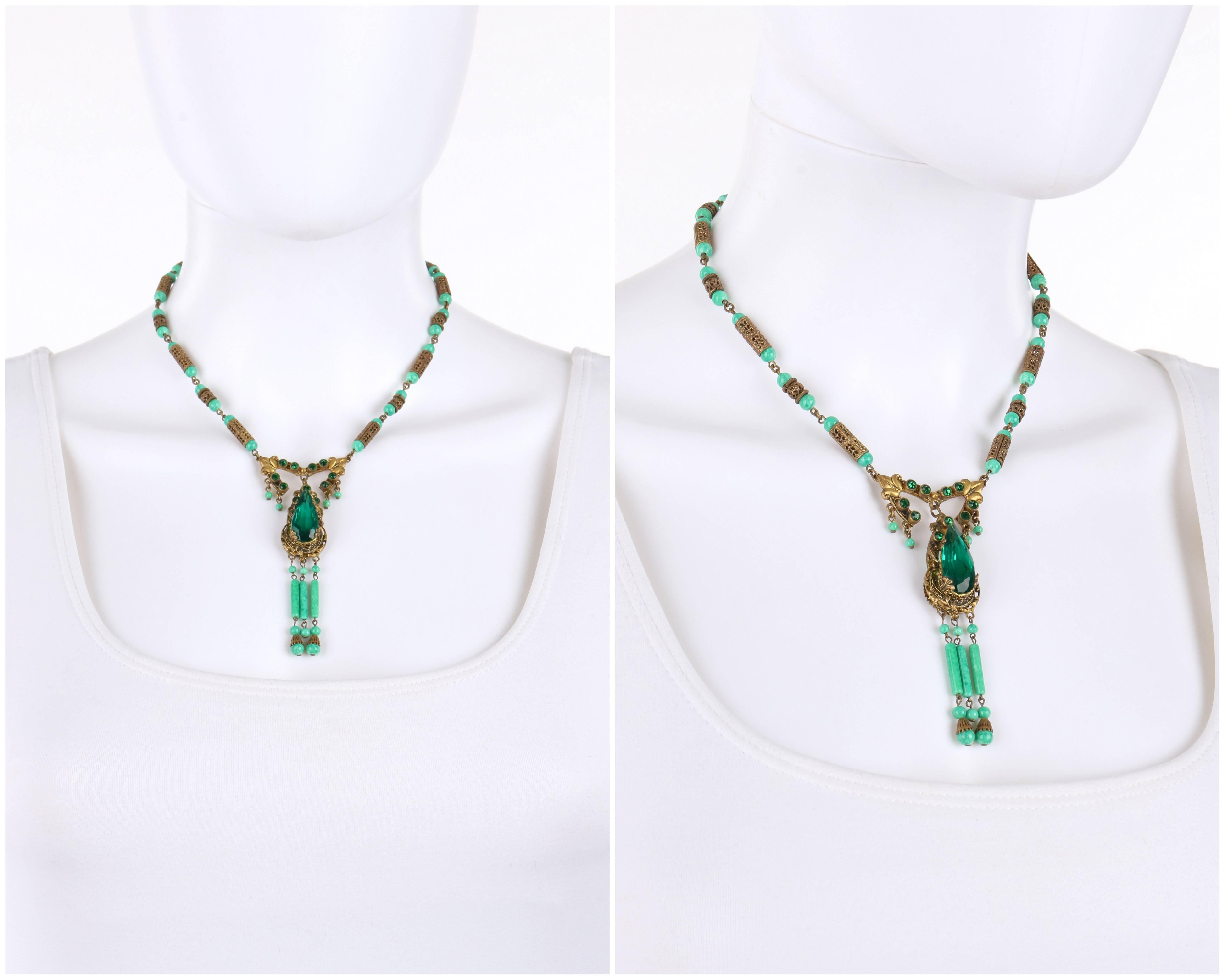 Vintage c.1920's Art Deco ornamental brass-tone and jade Czech pecking glass bead necklace. Ornamental brass-toned open work tear drop shaped pendant has large faceted emerald green crystals set in center and eleven small crystals set at top. Three