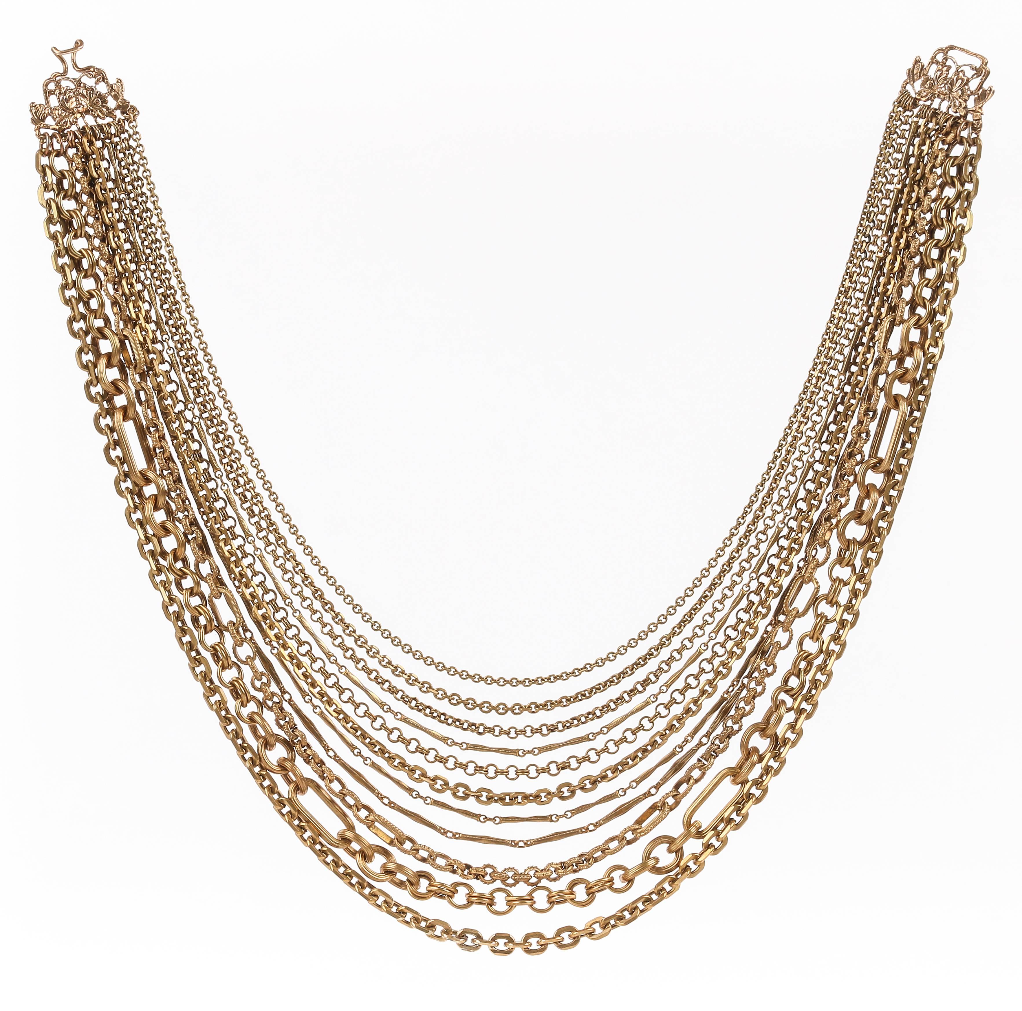 Stephen Dweck bronze multi-strand chain necklace. Eleven strands of varying sizes and styles of cable, double cable, bar, and figaro cable chains. Strands are connected by o-rings to a floral open work hook and bar clasp. Marked "Stephen