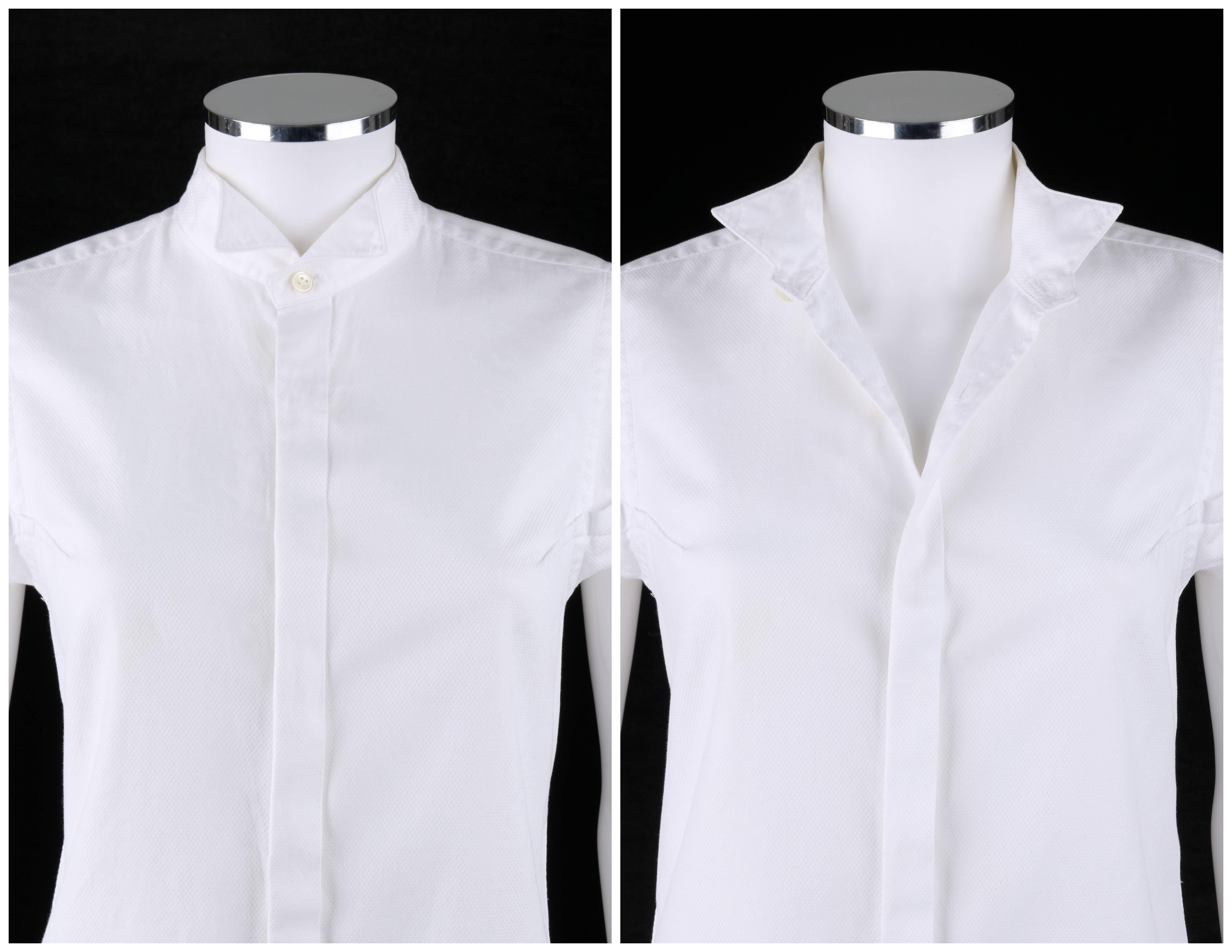 Comme des Garcons white cotton pique button front tuxedo shirt designed by Junya Wantanabe. Cap sleeves with raw edge detail. Seven front hidden button closures. Standing winged collar (can be worn up or folded down). Exposed bust darts. Back yoke