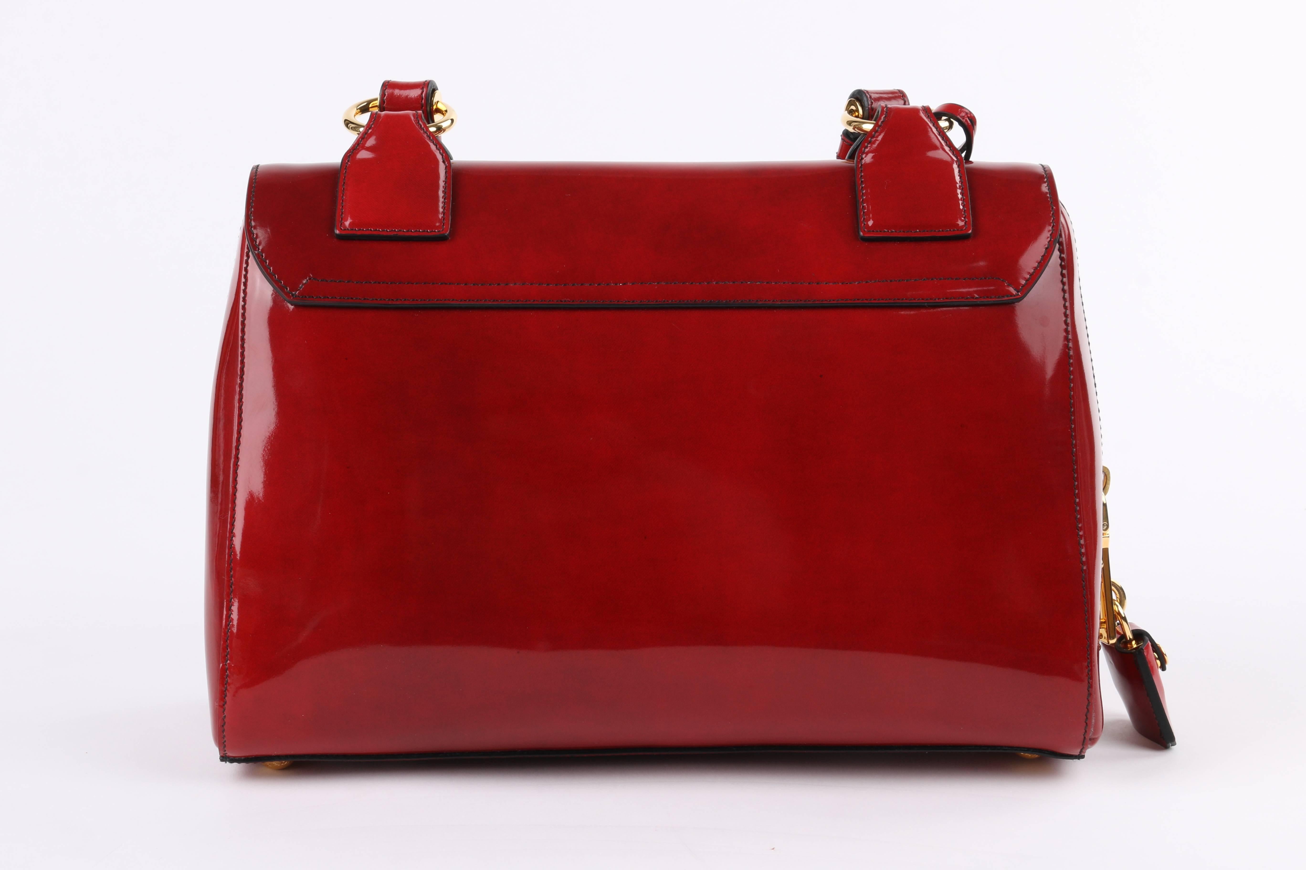 Prada Autumn/Winter 2012 scarlet red spazzolato (brushed/patent) leather turn lock purse. Runway look #13. Scarlet smoke (scarlatto fume) red calfskin leather body. Single top handle with adjustable gold-toned buckles on either side. Flap top with