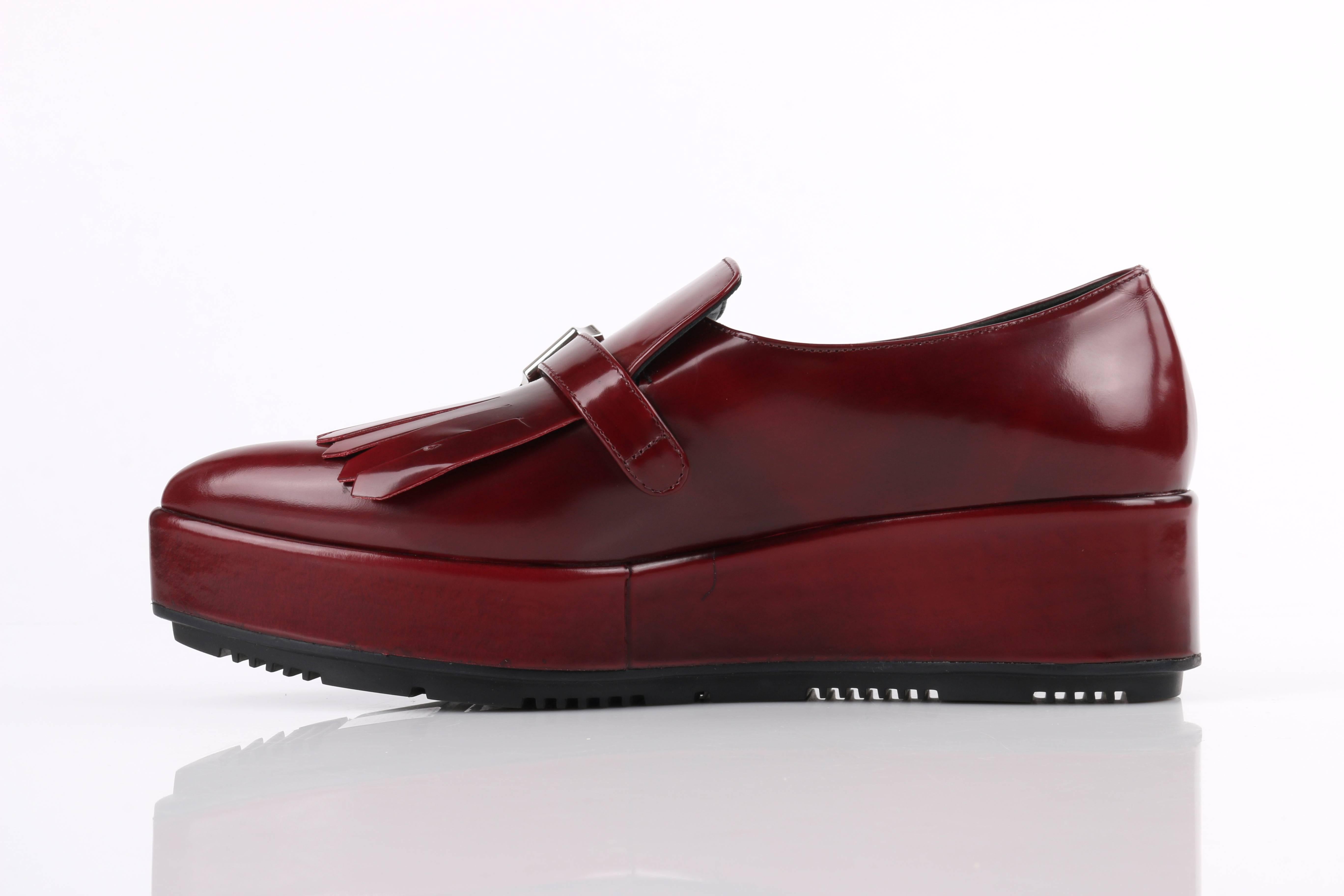 Prada Autumn/Winter 2013 Burgundy red spazzolato (patent/brushed) leather platform oxford. Burgundy red smoke patent (spazzolato fume) calfskin leather body. Pointed toe. Front kiltie fringe detail. Single adjustable strap along top with