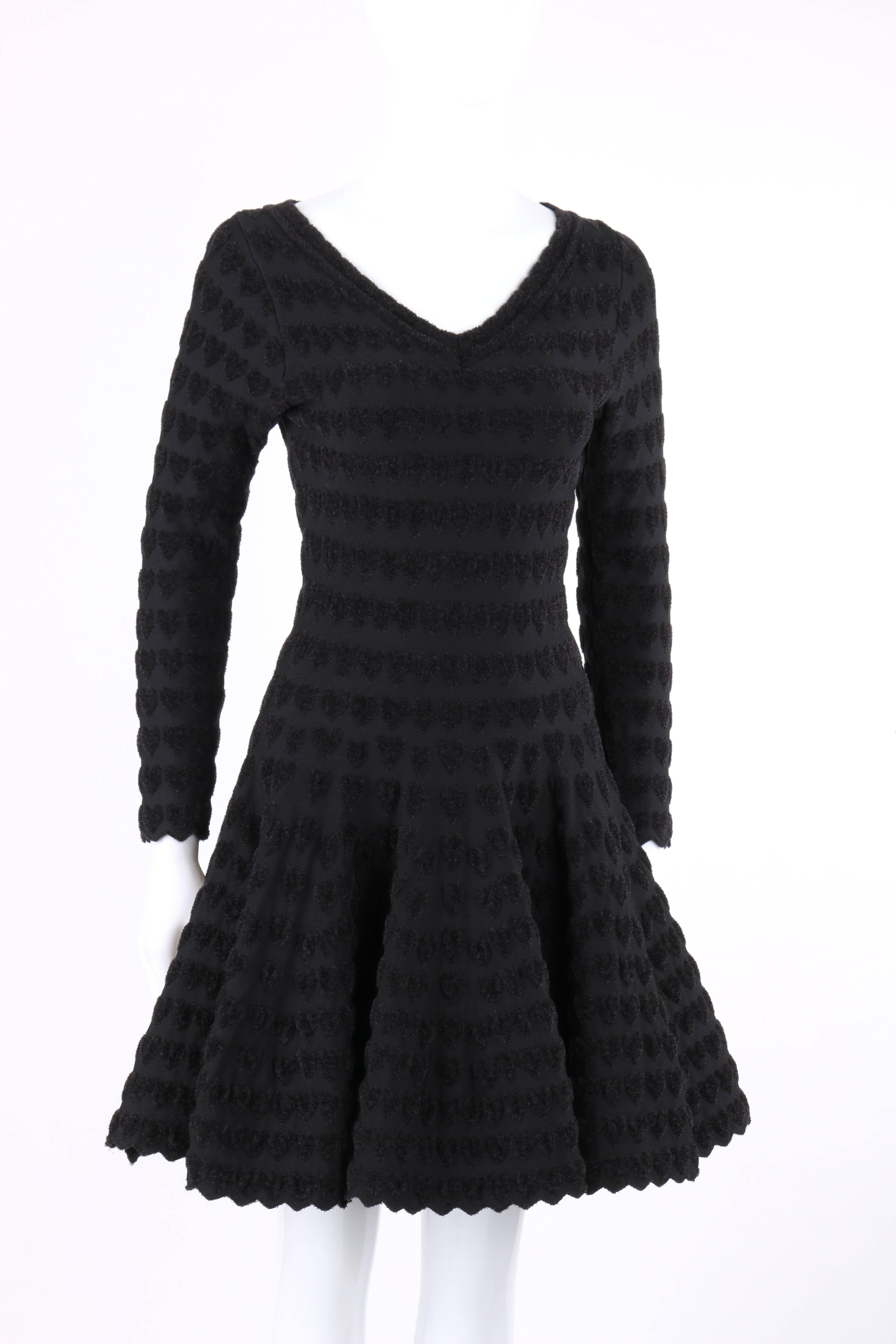 Alaia Paris black heart patterned knit cocktail dress. Black on black plush heart patterned knit. V-neckline. Long sleeves. Drop waist. Full skirt. Zigzag hem at cuffs and hemline. Slip-on. Fit and flare style. Unlined. Unmarked Fabric Content: