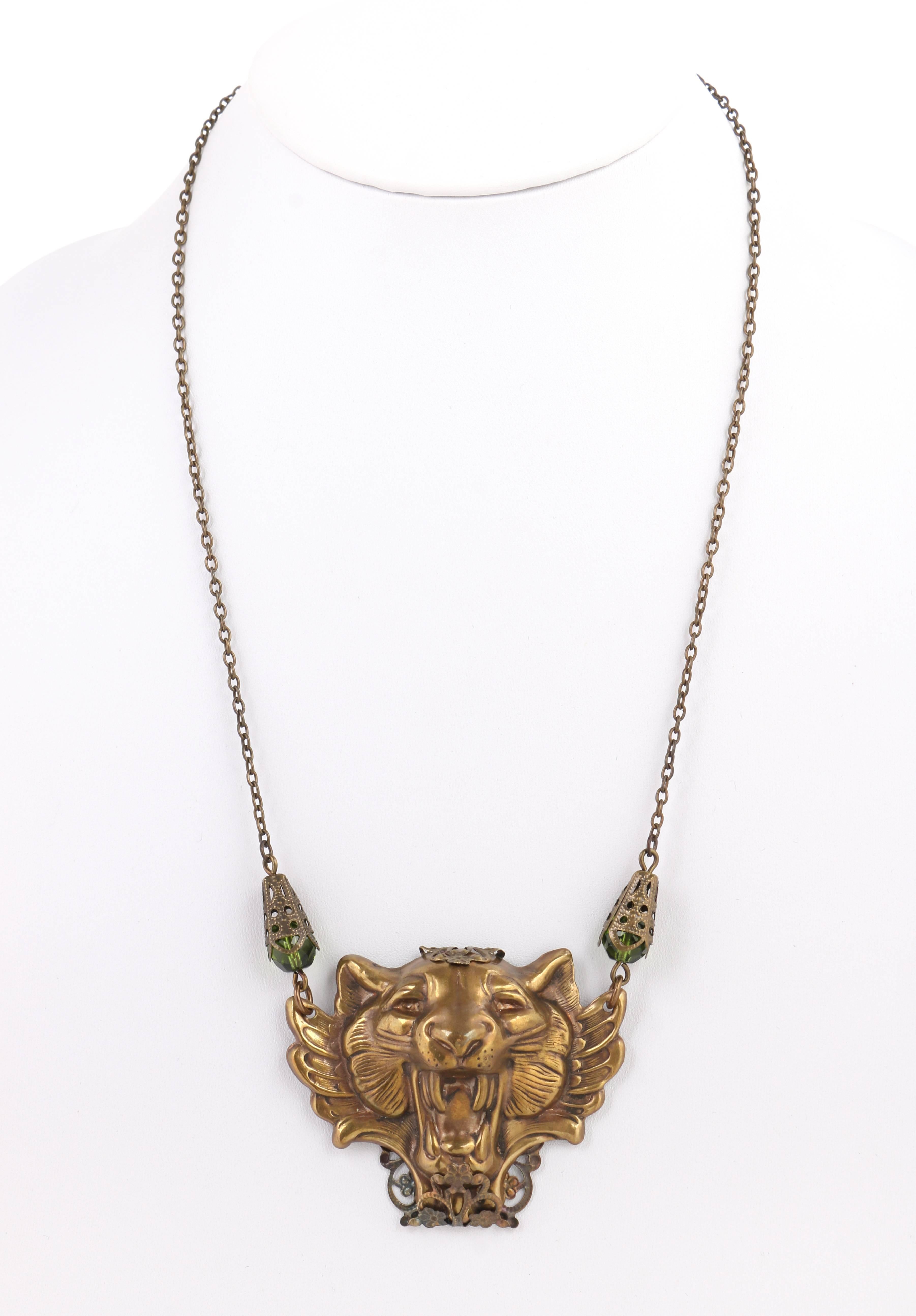 Vintage brass pressed metal winged tiger / lion / cat head statement pendant necklace. Brass-toned metal winged large wild cat head pendant. Floral open work filigree brass-toned metal design wrapped around at back of pendant from top to bottom.