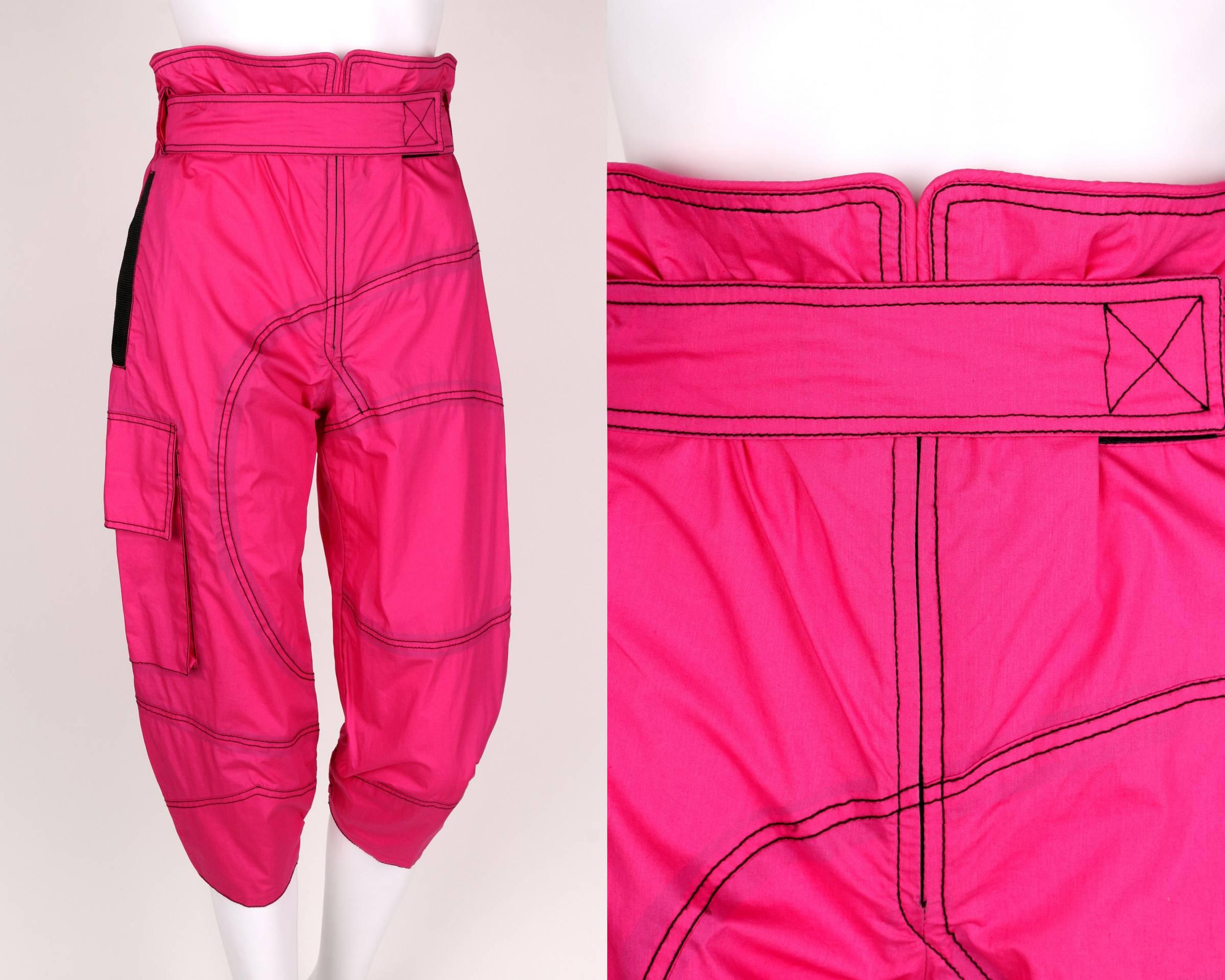 Emilio Pucci bright pink high-waisted windbreaker capris. Fabric belt at front with velcro closure. Elastic waistline at back. Center front zip fly. Large patch pocket with flap at right side. Right inseam hip pocket with black nylon webbing detail