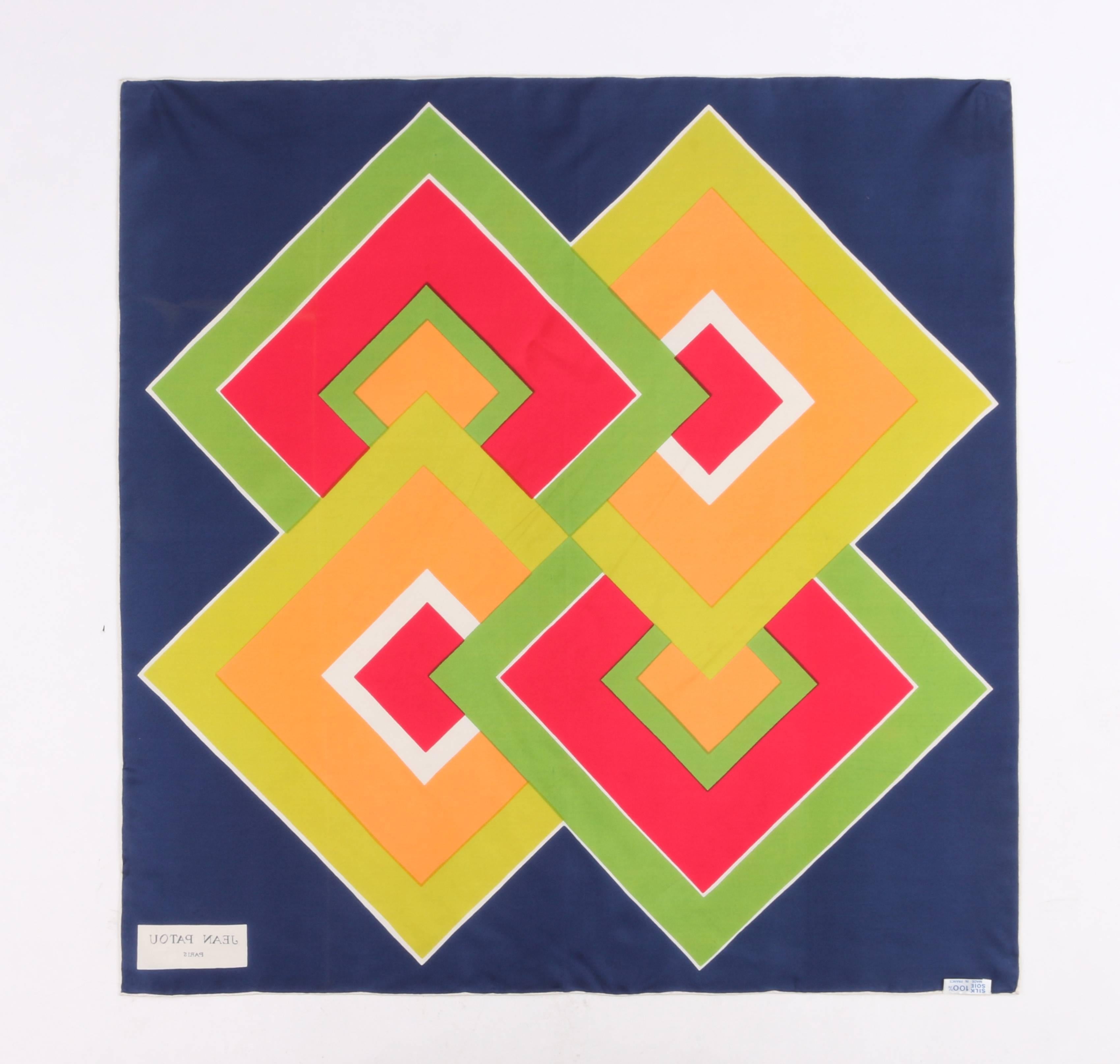 Vintage Jean Patou c.1960's navy blue geometric op art print silk scarf. Designed by Michel Goma. Navy blue background. Central overlapping square op art print at center in shades of yellow, orange, green, fuschia, and white. White hand rolled edge.