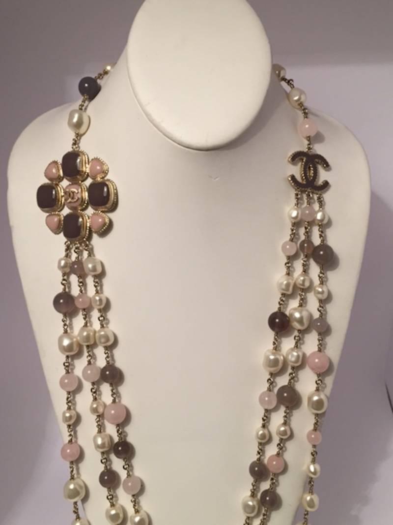 From the Chanel Spring 2012 collection. The necklace consists of three strands of faux Baroque pearl beads in 8 and 12 mm sizes and 10 mm rose quartz and grey agate beads. On one side, the three strands are suspended from a 2 inch (5.5 cm) medallion