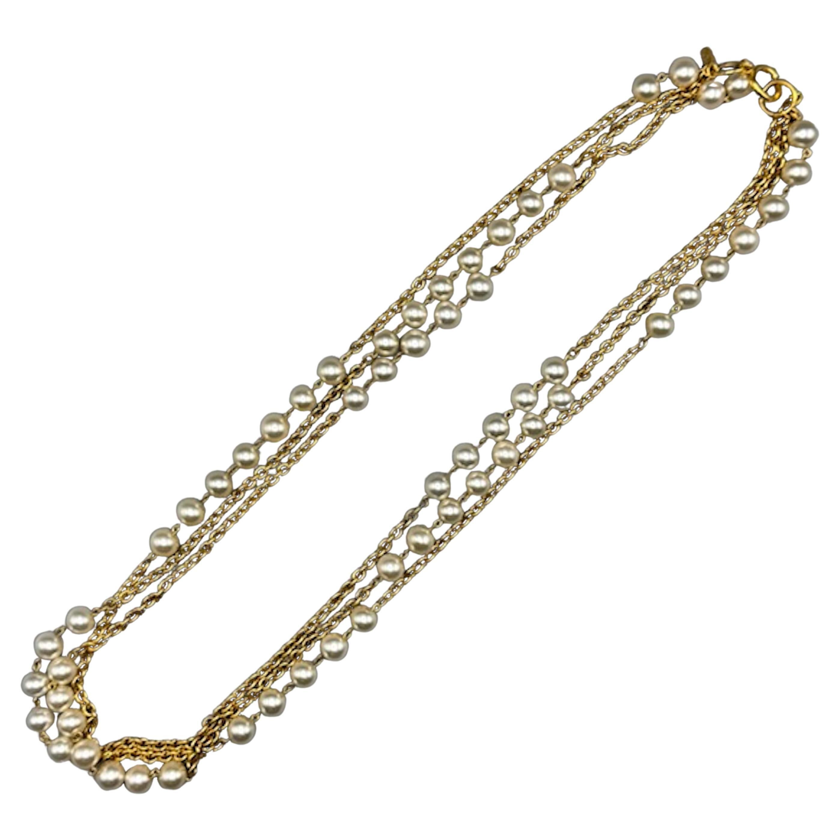 Ce collier est un élégant et classique collier Chanel à trois rangs, datant du début ou du milieu des années 1980. Le collier est composé de chaînes en or riche entrecoupées de groupes de 2, 5 et 7 perles centrales en faux verre. Le brin supérieur