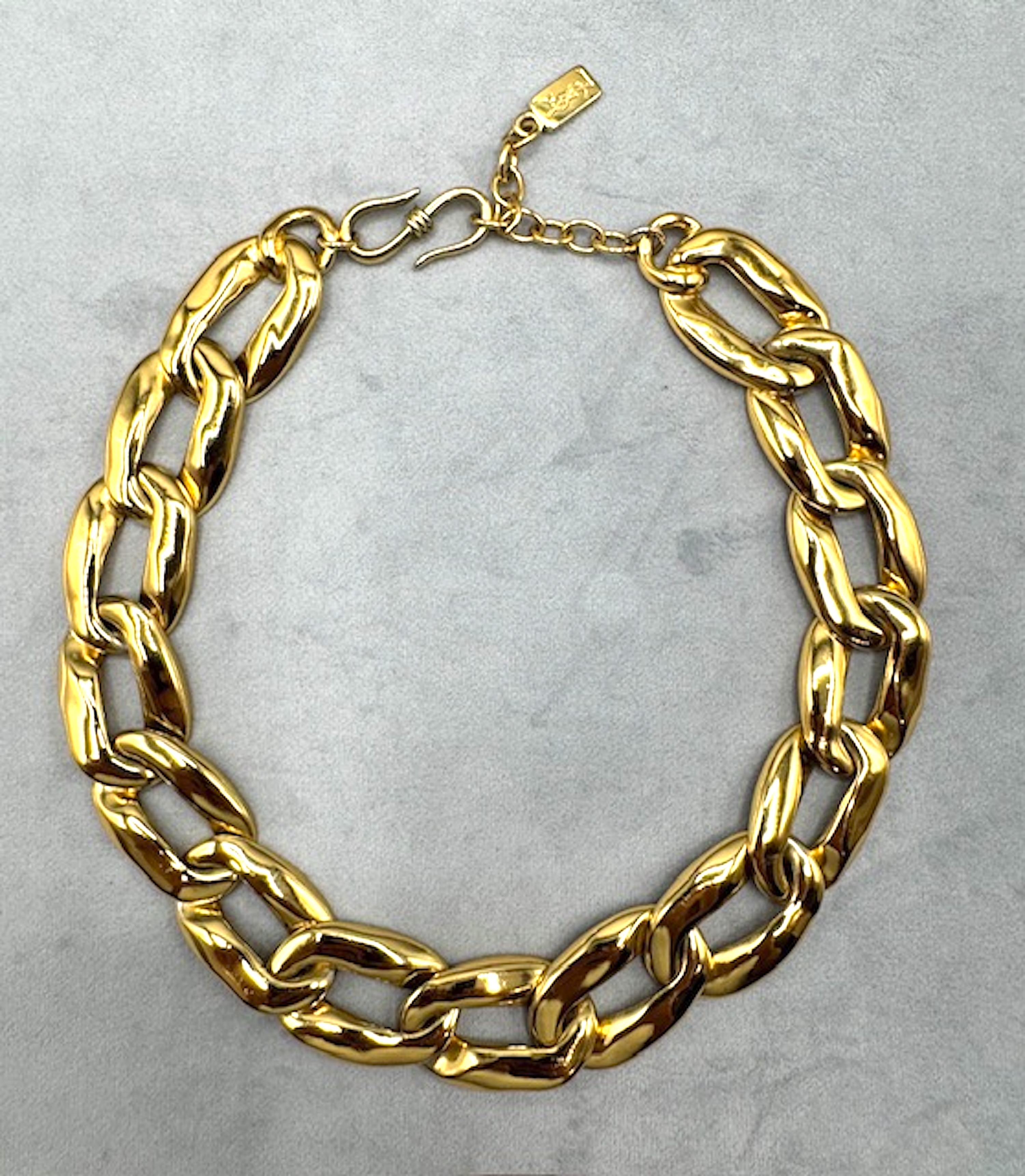 Il design classico degli anni '80 è questo piatto d'oro.  Yves Saint Laurent  collana di link.
I link sono  alto 5 centimetri e con strass incastonati. A partire dalla maglia centrale con strass, ogni maglia misura 1,5
