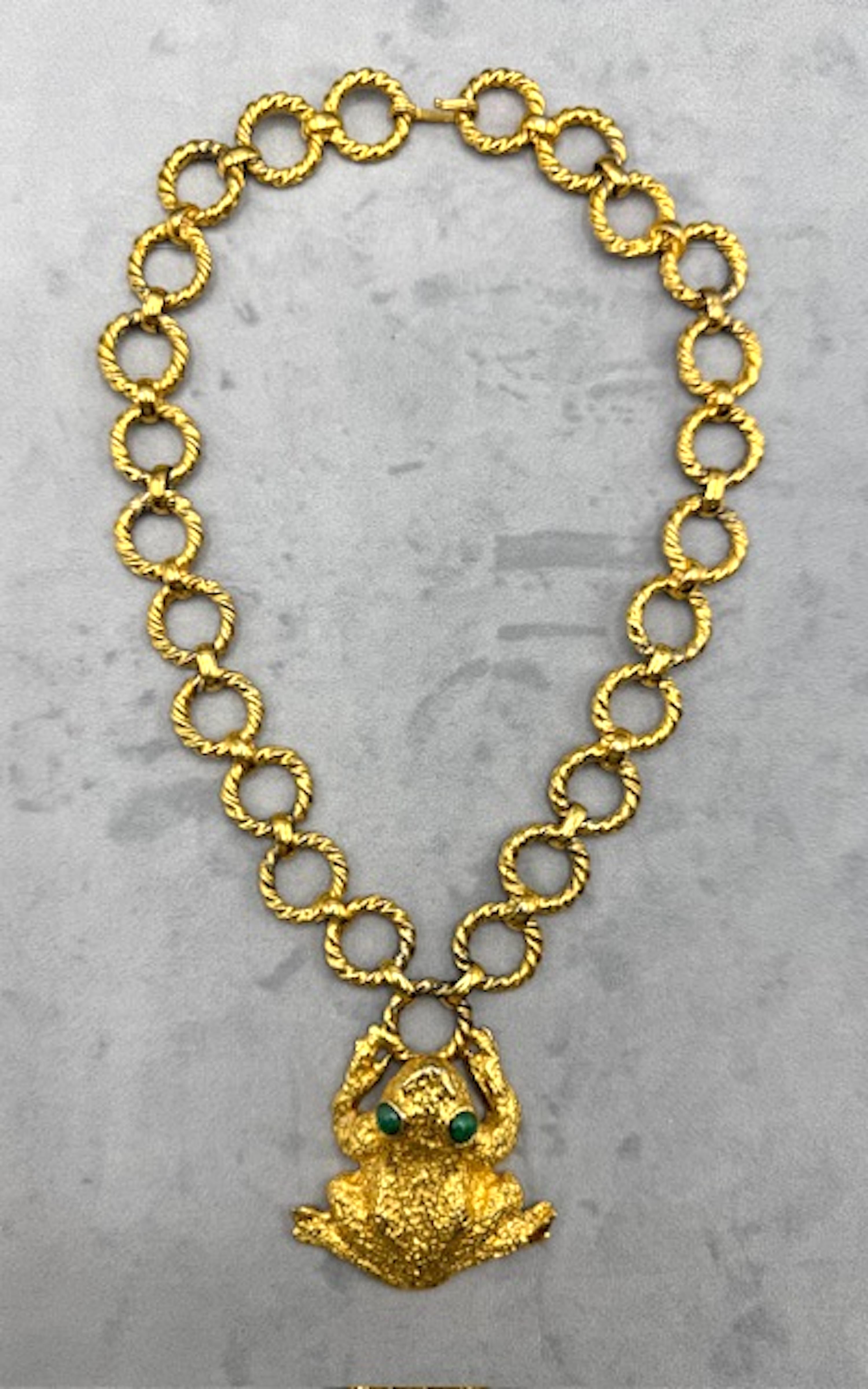 Questa grande collana in lastra d'oro con un grande ciondolo a forma di rana è una vera e propria dichiarazione ed è stata disegnata da Mimi di Niscemi (Mimi di N) nel 1971. La finitura oro brillante è perfetta per gli occhi cabochon in vetro verde