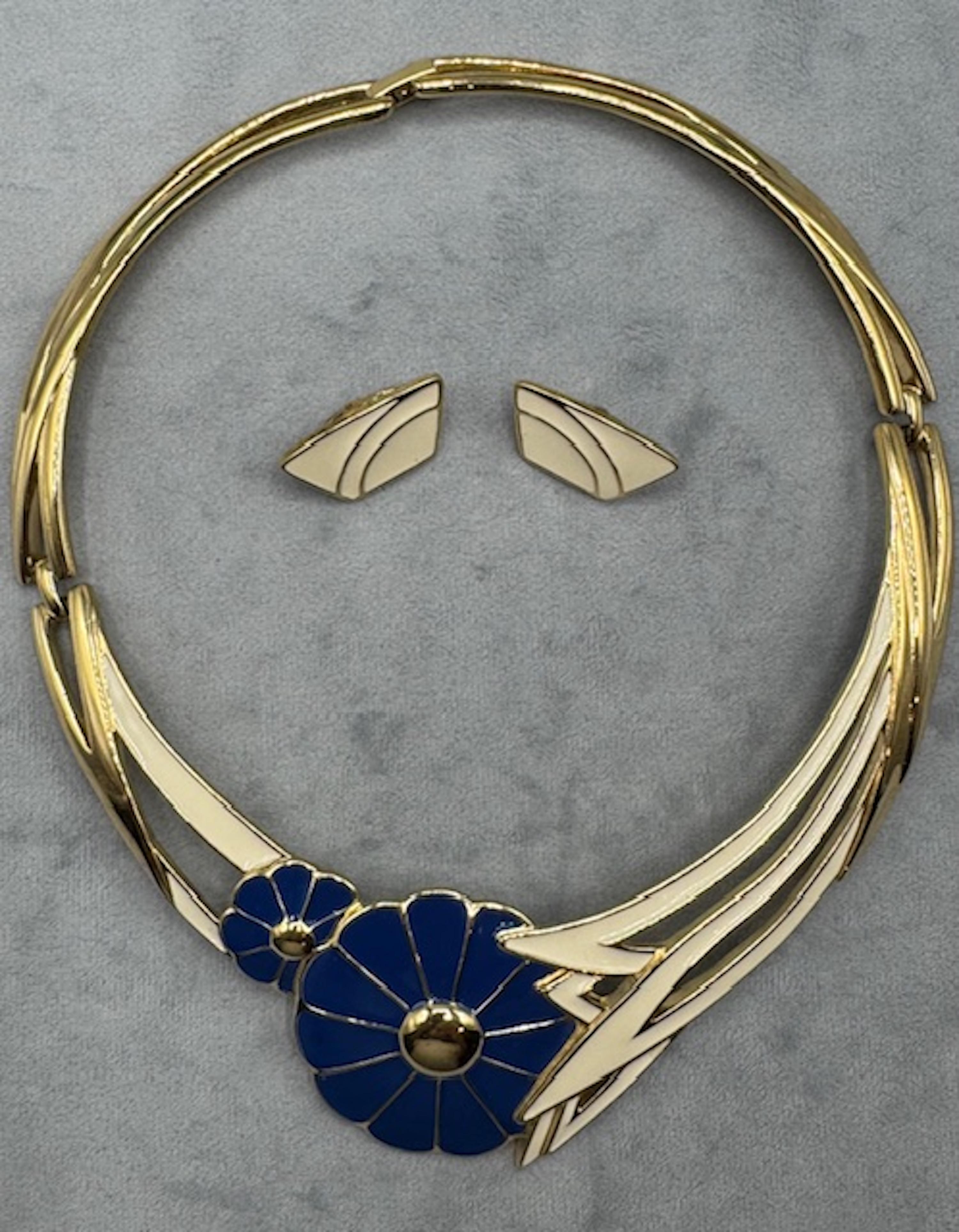 Entra in un elegante stile vintage con questa straordinaria collana di Trifari degli anni '80. Caratterizzato da un design rigido e a colletto, questo pezzo è splendidamente realizzato con smalto lucido blu e bianco in un motivo floreale che ricorda