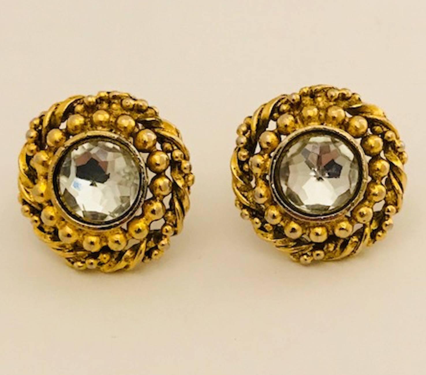 A very nice pair of 1970 to 1980 Chanel button clip earrings featuring a twisted rope with bead design setting with central faceted dome crystal stone. Each earring measures one inch in diameter. Very good condition with no wear to the gold plate.