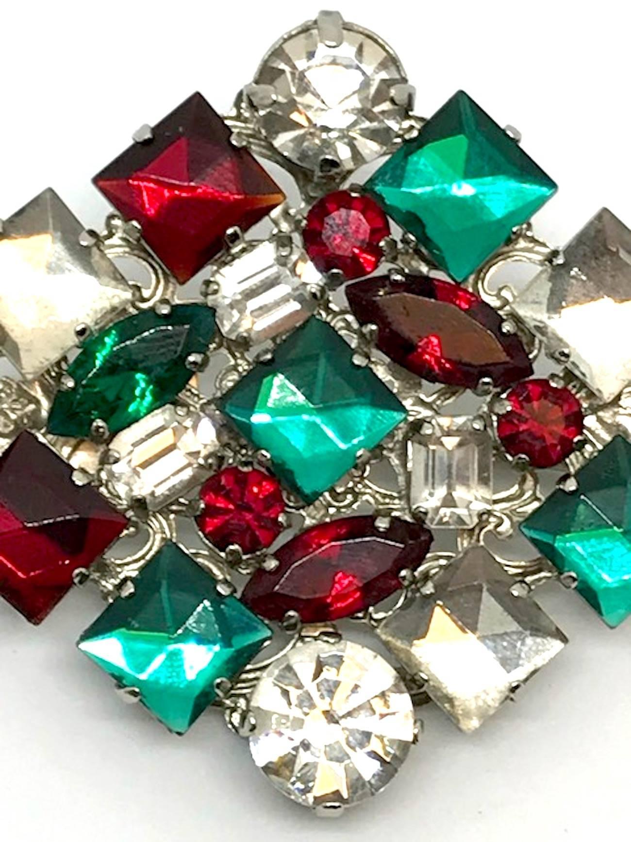 A lovely and large pin by De Liguoro from the collection of Italian actress Elsa Martinelli. The pin is rhodium plate with red and green square, round and marquise stones and clear square and round stones. The diamond form pin is accented with two