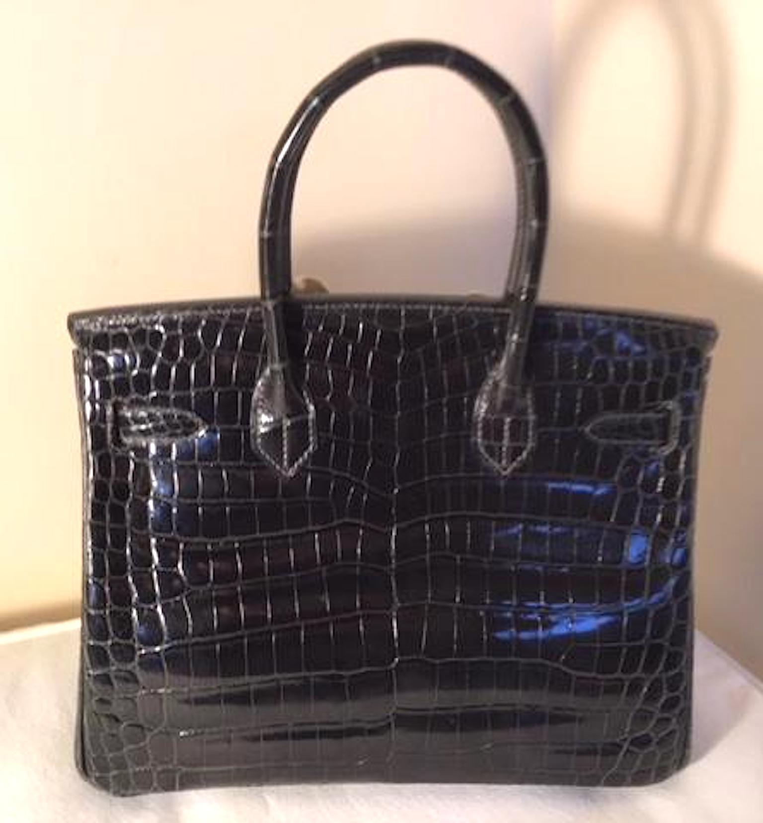 A rare color of shiny graphite is this Niloticus crocodile Hermes Birkin. Only the finest Niloticus crocodile hide is used. It has a larger pattern than the Porosus and has a shiny finish. The bag measures 30 cm x 22 cm x15 cm and is the most