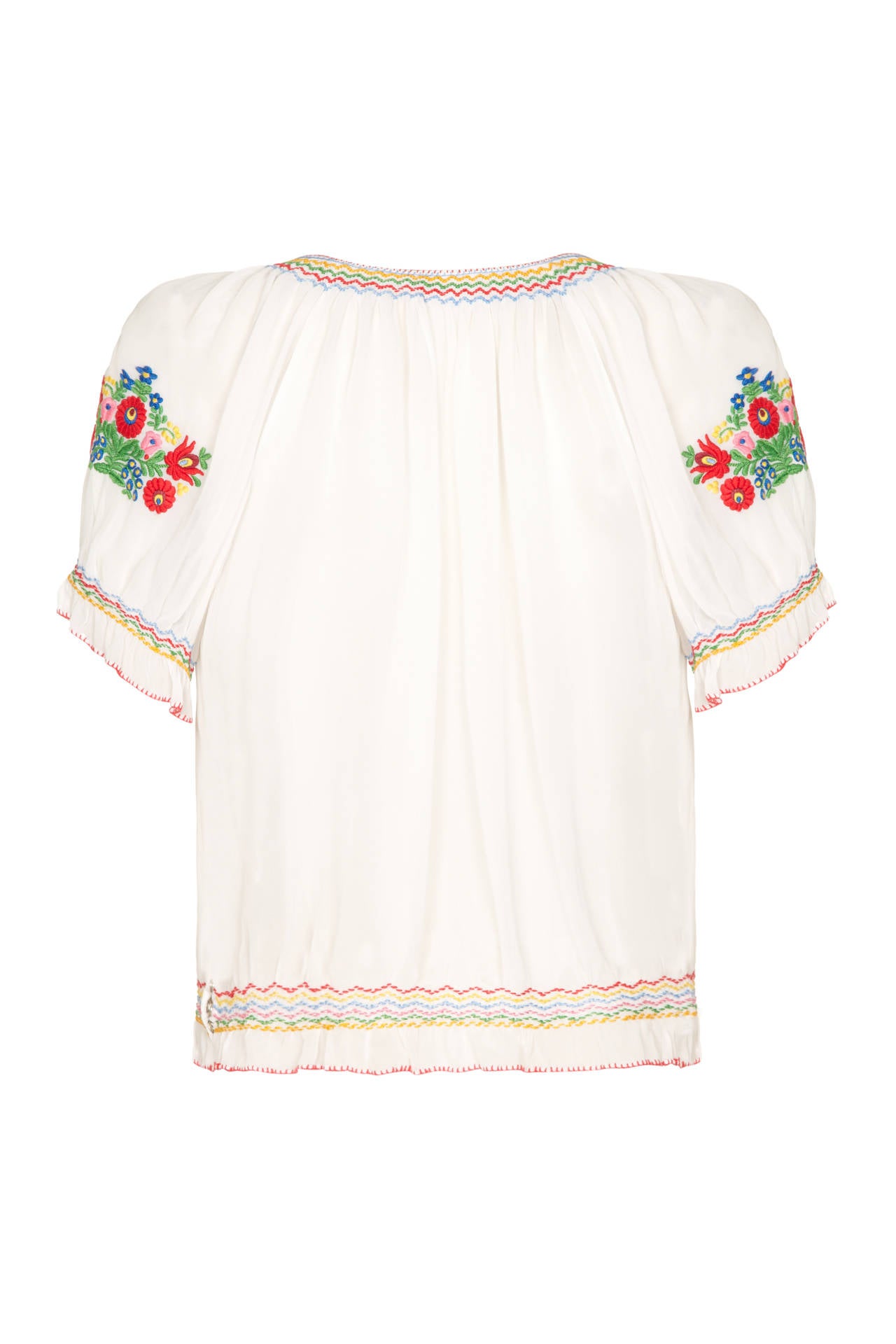 Beautiful white Hungarian blouse from the 1950s with lovely, multi-coloured floral embroidery.  This example is slightly sheer with short gathered sleeves, a tie at the neckline and is in excellent condition. It is a loose fitting style and