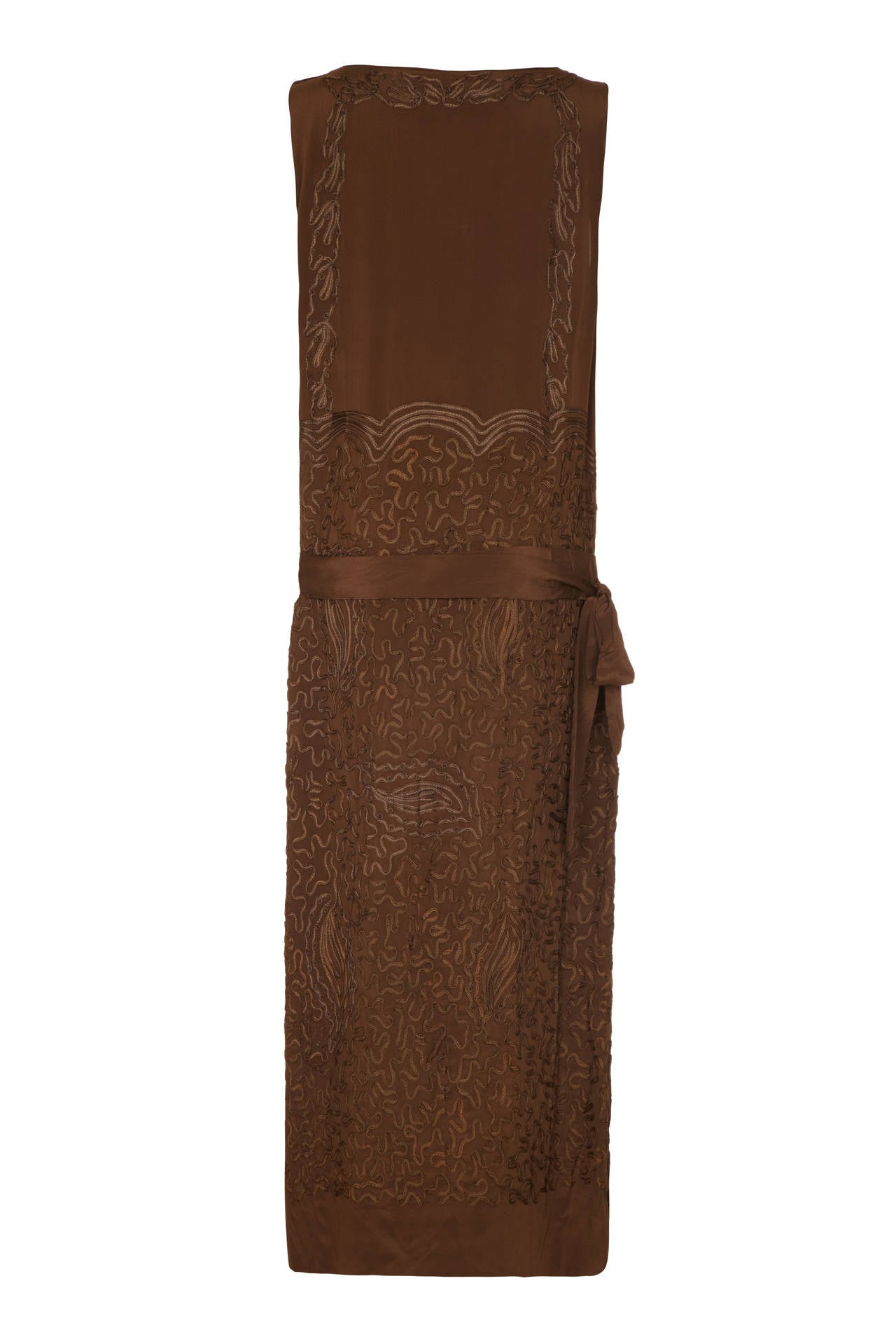 Beautiful late 1910’s /early 1920’s brown silk flapper dress with intricate ribbon applique throughout the calf length skirt and around the edges of the sleeveless bodice. In typical flapper style it is straight cut with a dropped waist and matching