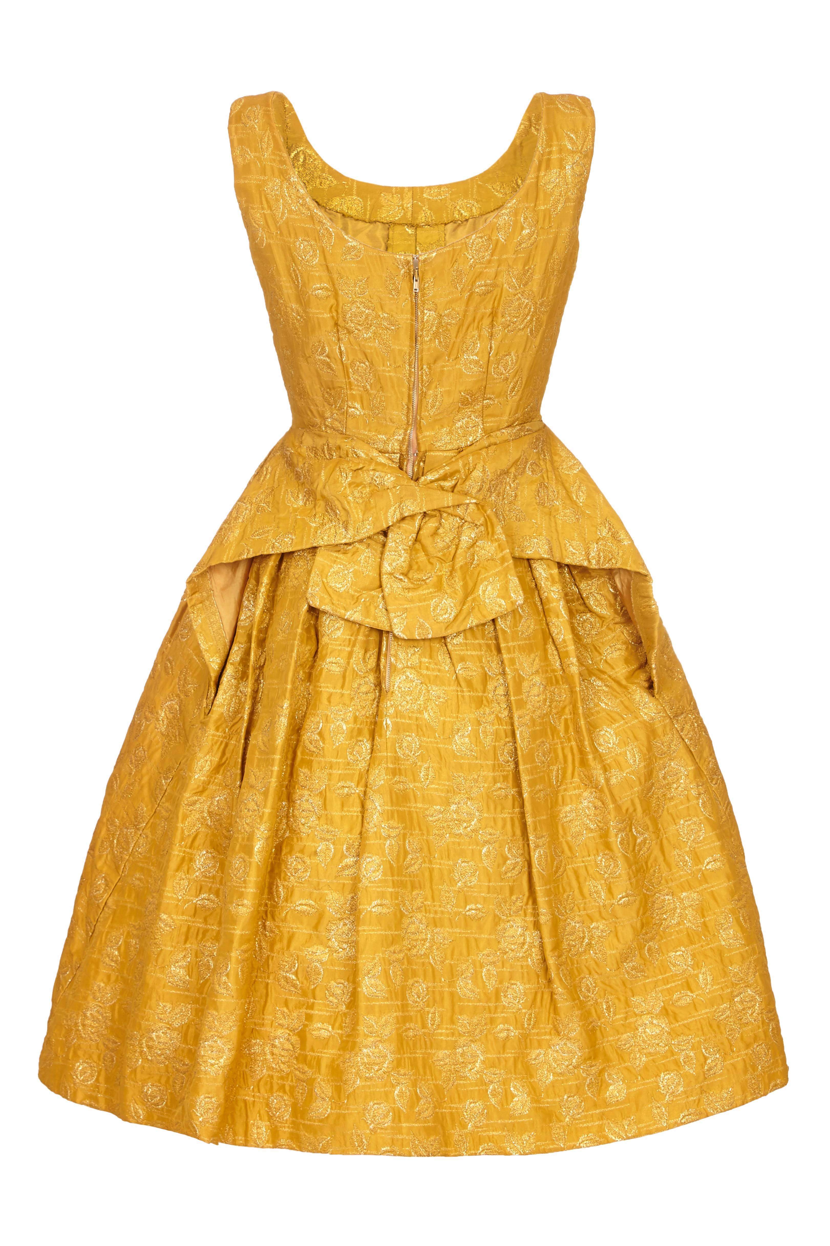 Amazing vintage 1950s gold floral brocade dress from British designer Frank Usher. This sleeveless dress has a hooped canvas petticoat attached inside which keeps the fullness in the skirt and also extends up with boning to the waist.  It fastens at