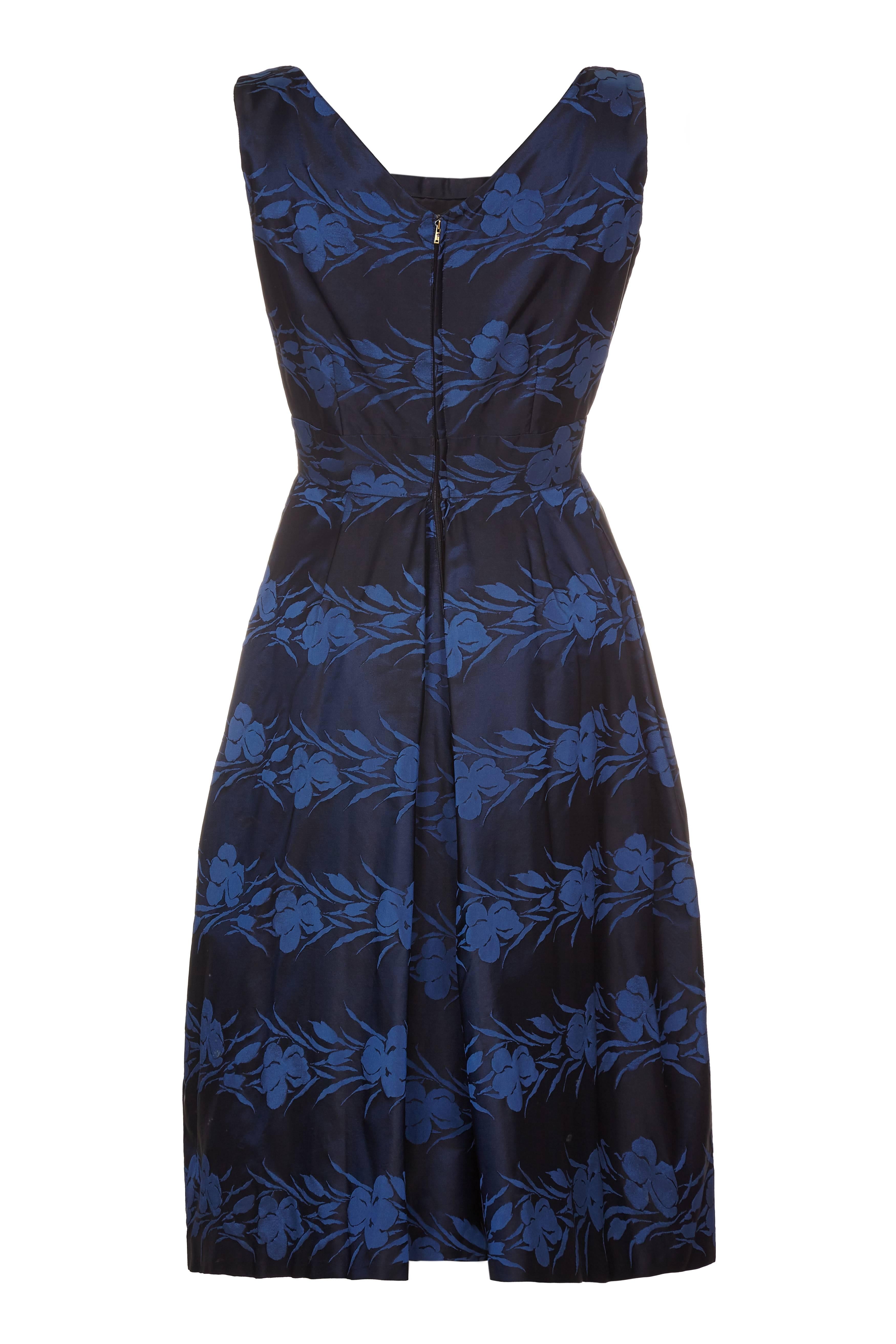 1950s Susan Small silk formal dress in a beautiful midnight blue and french blue floral print. Nipped in at the waist with a fabric rose and bow detail on the waist band, beautifully shaped and lined in a high quality cotton. Darted at the bust and