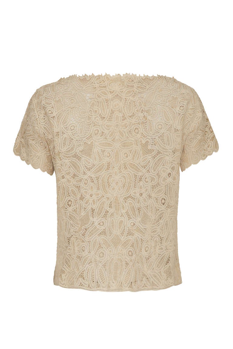 A very pretty, delicate and light cream floral lace blouse with short sleeves and a small collar on the front.  The blouse fastens down the front with poppers and is shaped with little tucks at the waist.