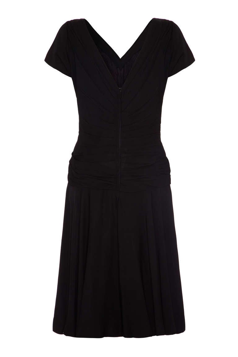 Fantastico abito nero della stilista americana Ceil Chapman.  Caratterizzato da un grazioso incrocio e da un dettaglio di ruche sul davanti e da una sexy scollatura sulla schiena, questo è l'abito perfetto per le feste! Le maniche corte aggiungono